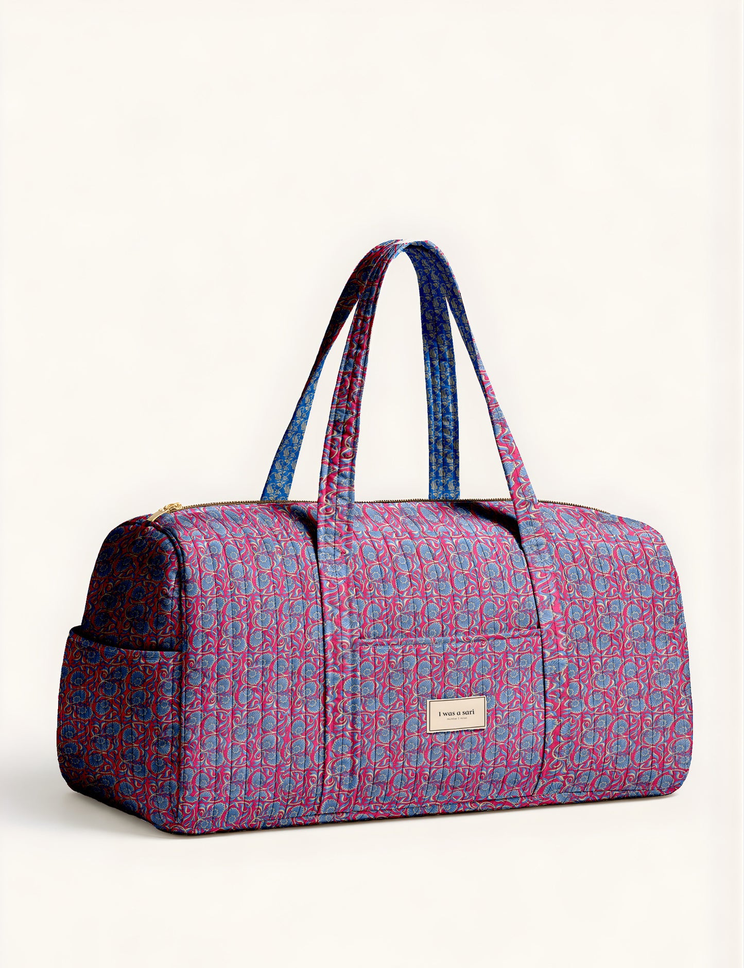 Quilted brown paisley barrel bag with double handles, front pocket, and gold zipper, shown in side angle view