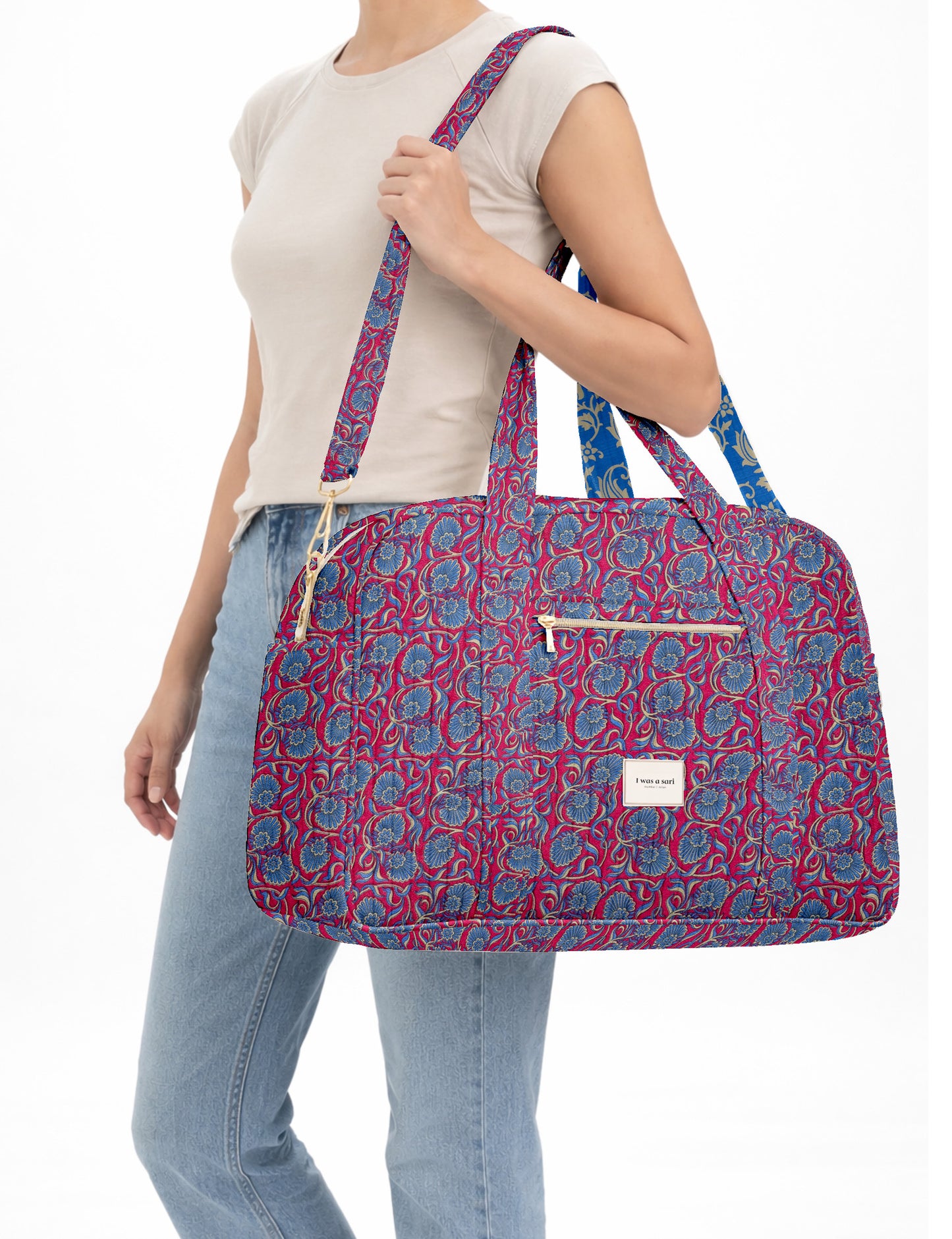 Brown quilted duffle bag with paisley pattern, front zip pocket, dual handles, and label reading "I was a sari"