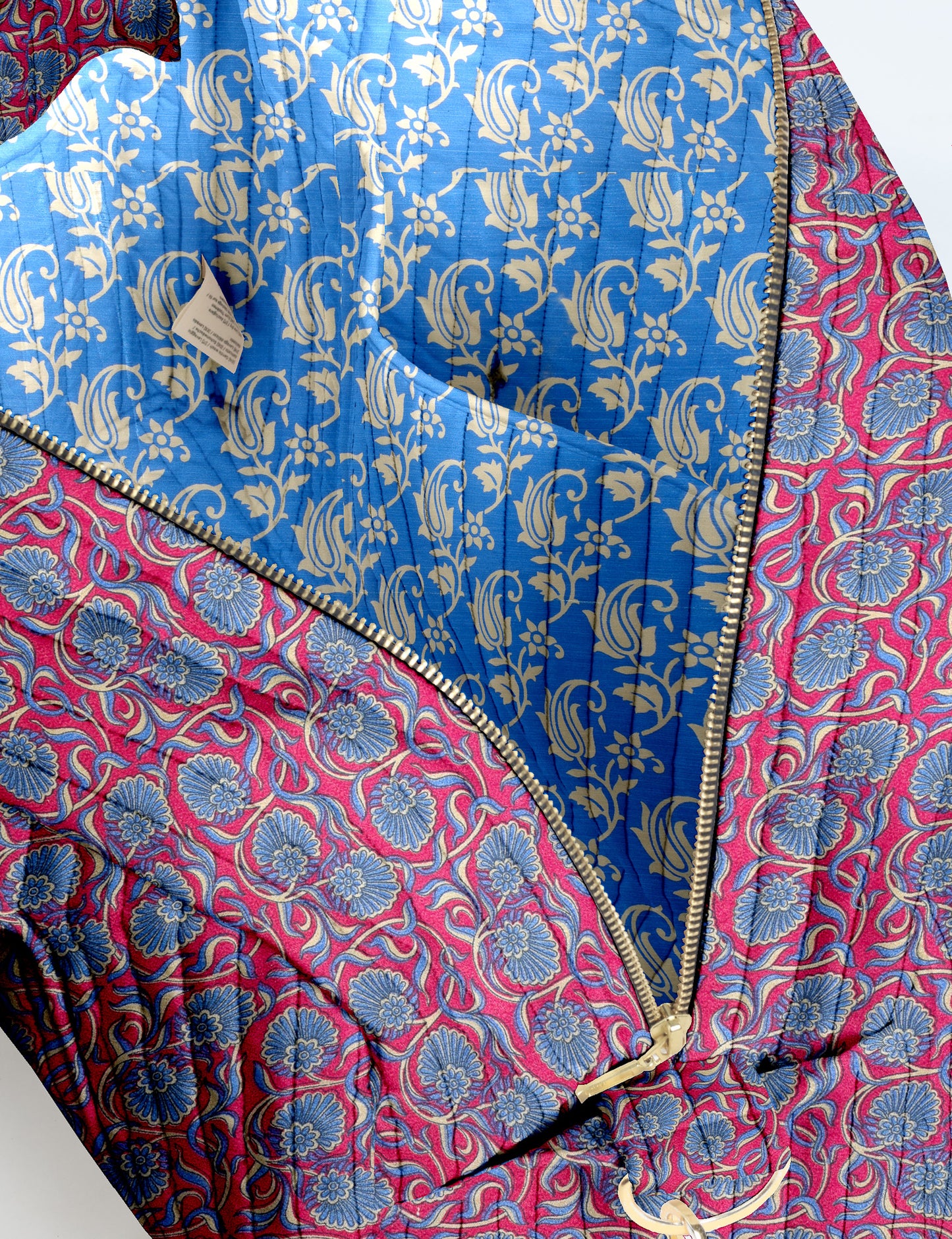 Brown quilted duffle bag with paisley pattern, front zip pocket, dual handles, and label reading "I was a sari"