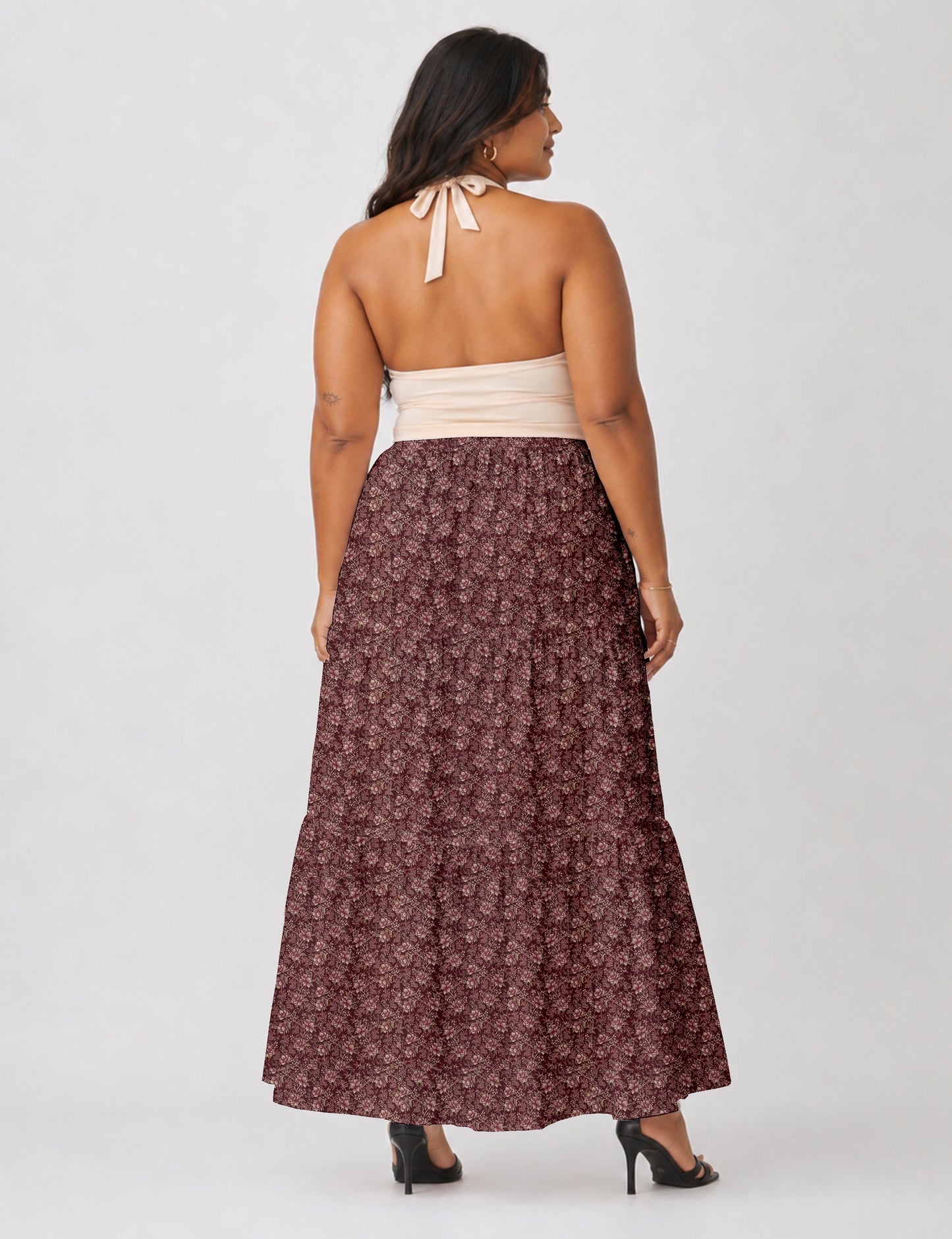 Woman wearing a yellow midi tiered skirt with a small geometric pattern, shown from the back, paired with beige top and