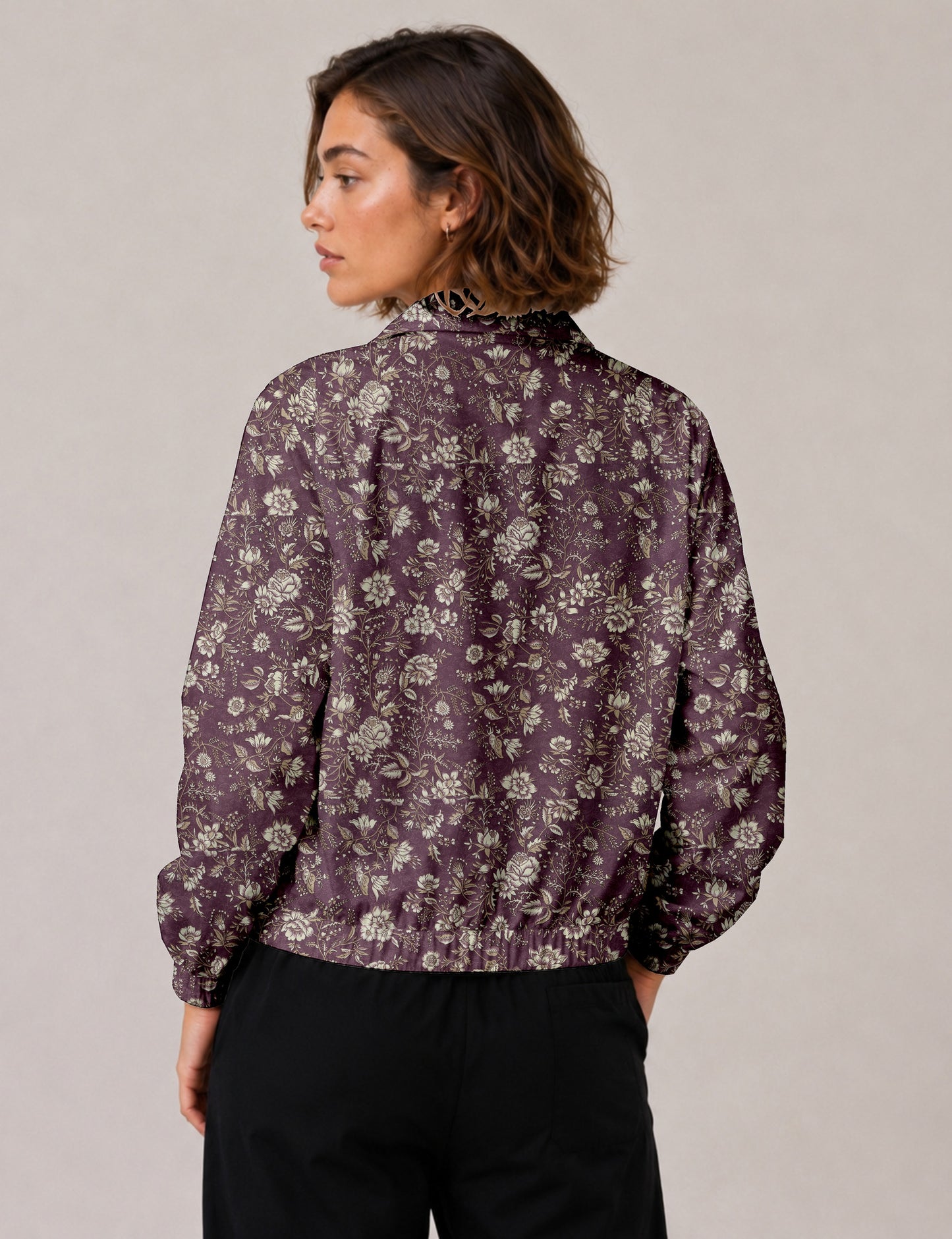 Woman wearing a yellow floral bomber jacket with front zipper, elastic cuffs, and side pockets, shown from front view