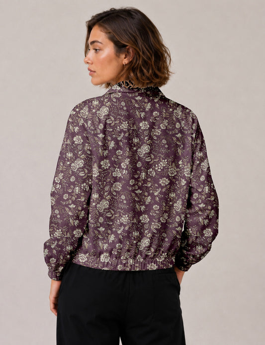 Woman wearing a yellow floral bomber jacket with front zipper, elastic cuffs, and side pockets, shown from front view