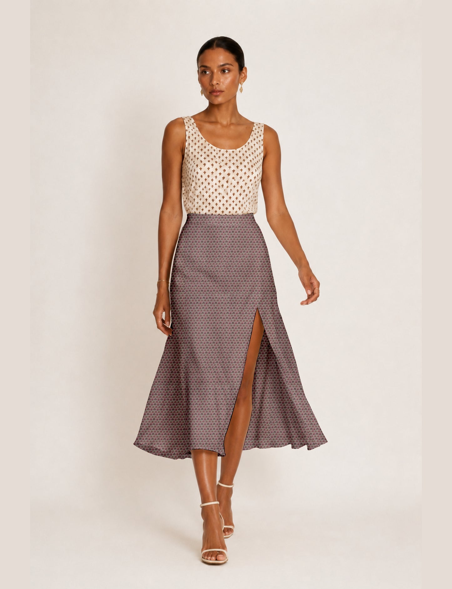 Woman wearing a yellow and black micro patterned A-line skirt with front slit, paired with beige sleeveless top and black