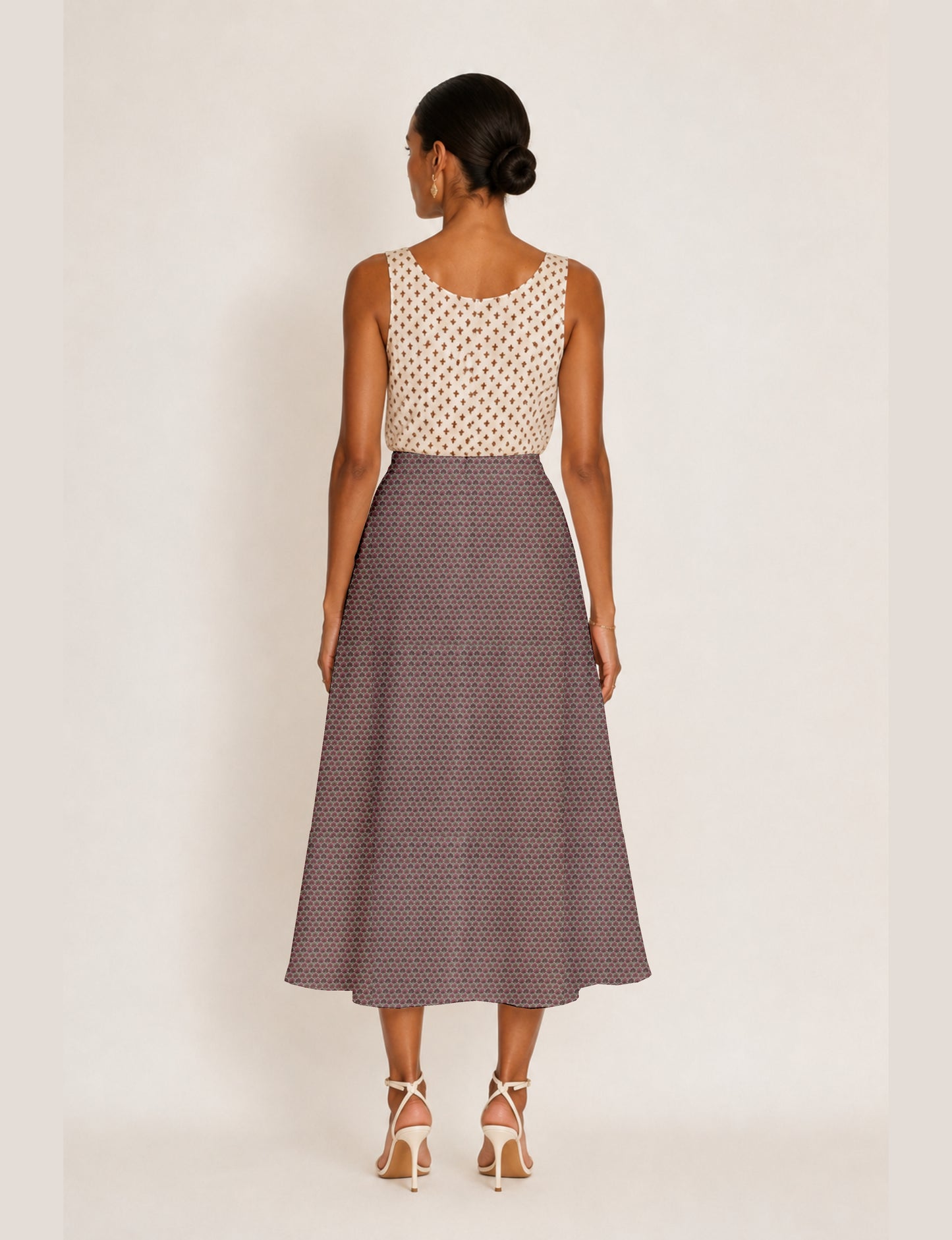 Woman wearing a yellow and black micro patterned A-line skirt with front slit, paired with beige sleeveless top and black