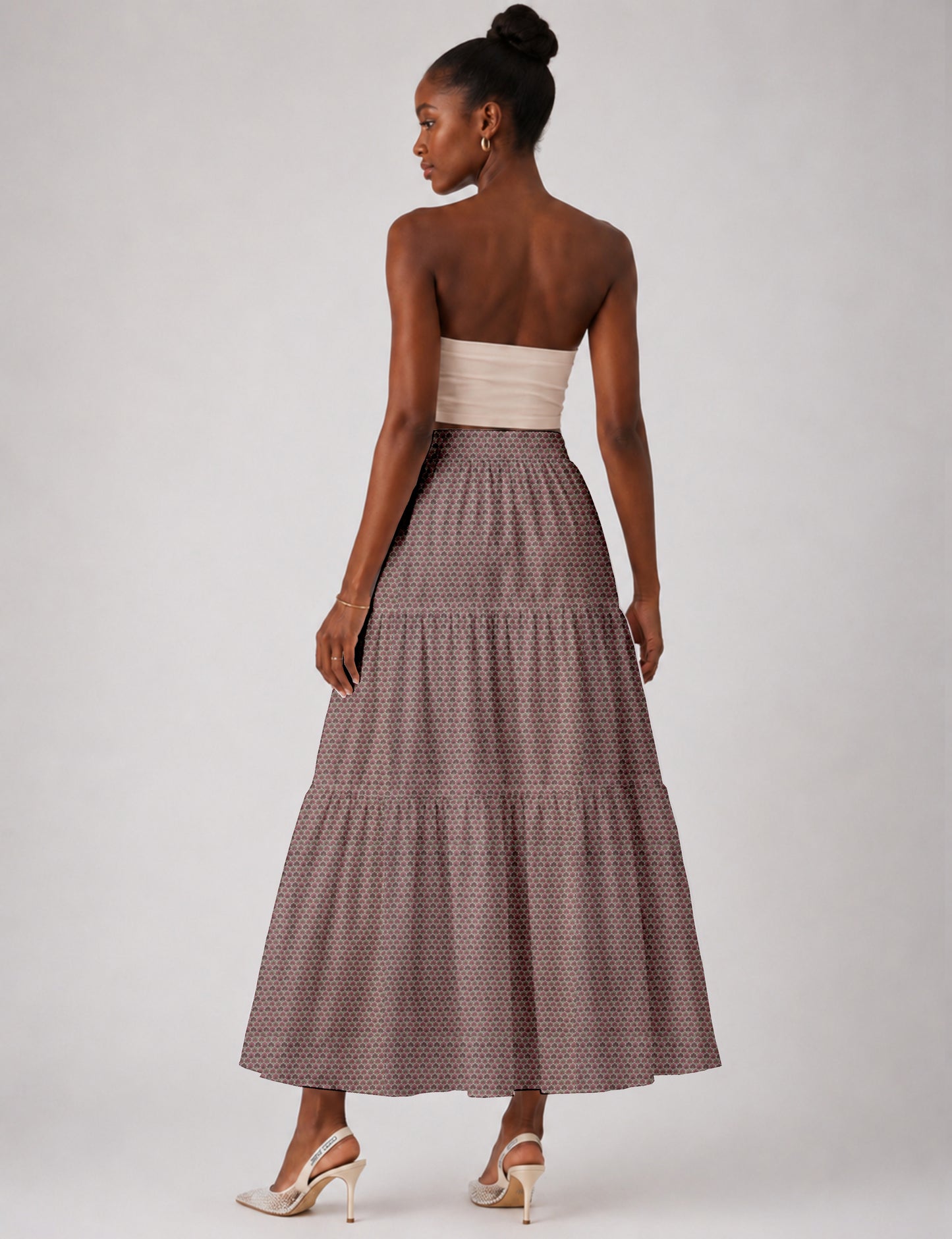 Woman wearing a yellow midi tiered skirt with a small geometric pattern, paired with a beige strapless top and white heels
