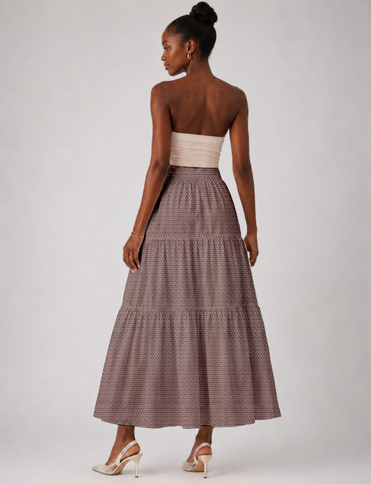 Woman wearing a yellow midi tiered skirt with a small geometric pattern, paired with a beige strapless top and white heels