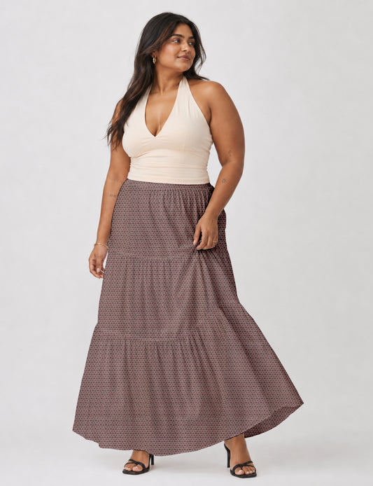 Woman wearing a yellow midi tiered skirt with a small geometric pattern, paired with a beige strapless top and white heels