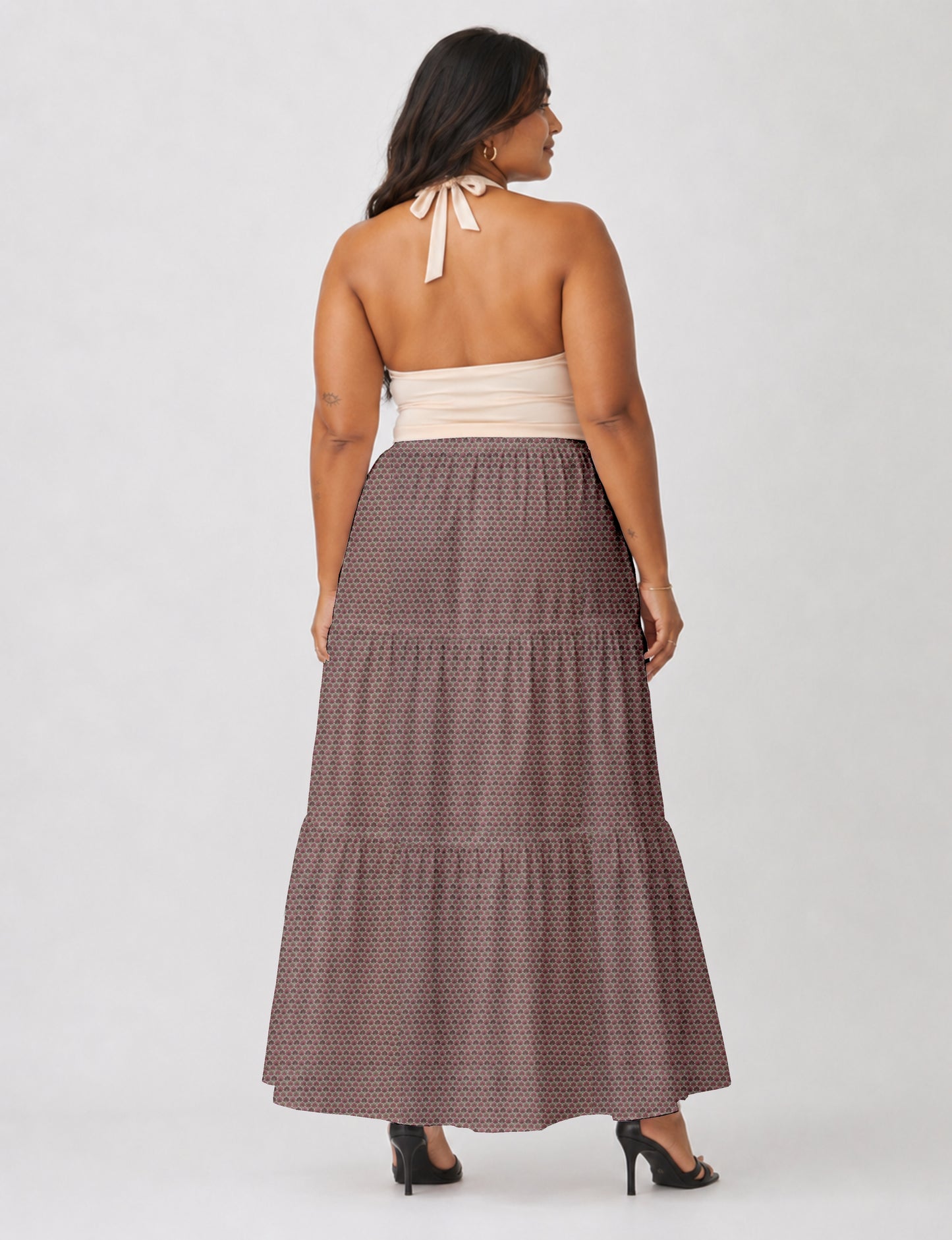 Woman wearing a yellow midi tiered skirt with a small geometric pattern, shown from the back, paired with beige top and
