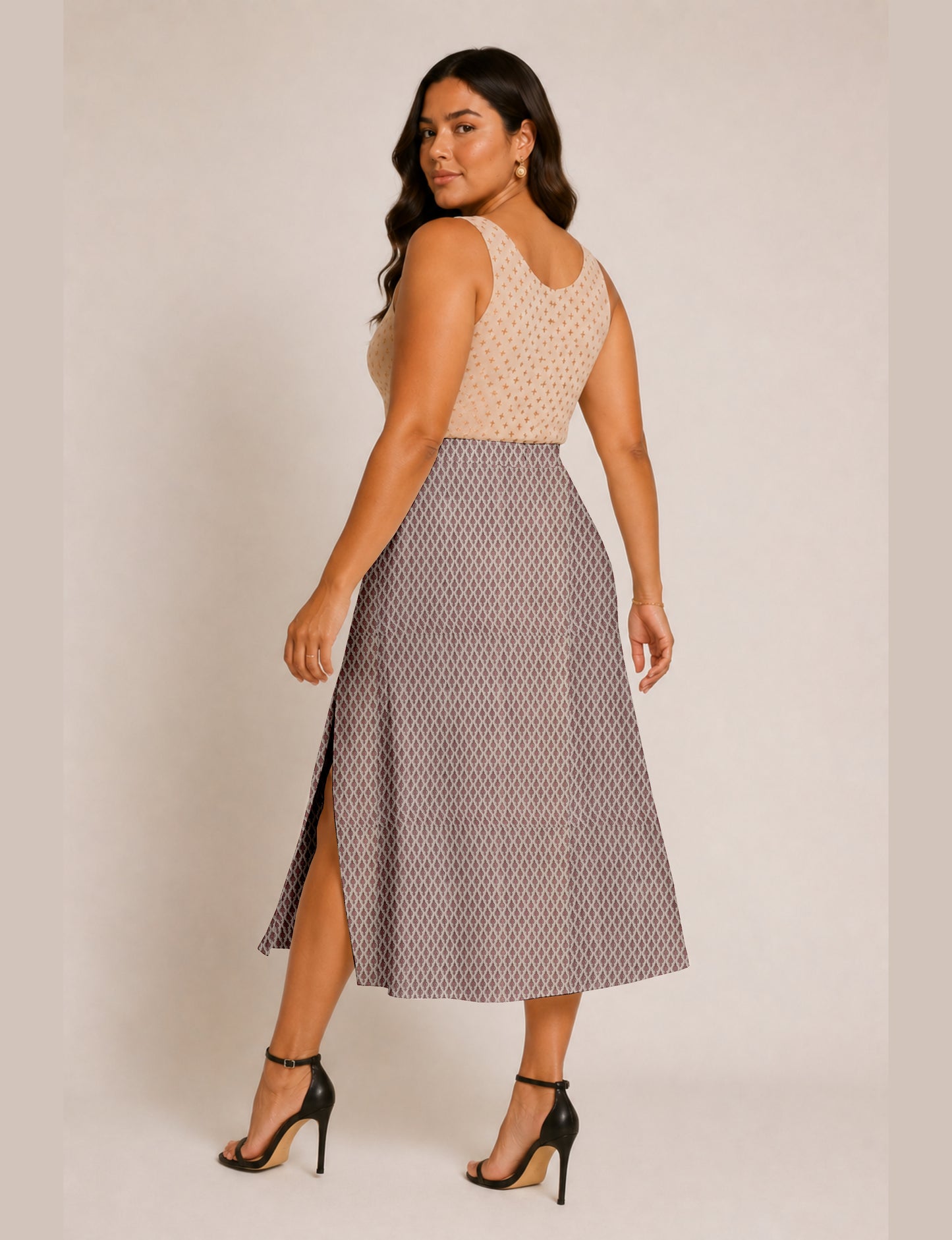 Woman wearing a yellow and black micro patterned A-line skirt with front slit, paired with beige sleeveless top and black
