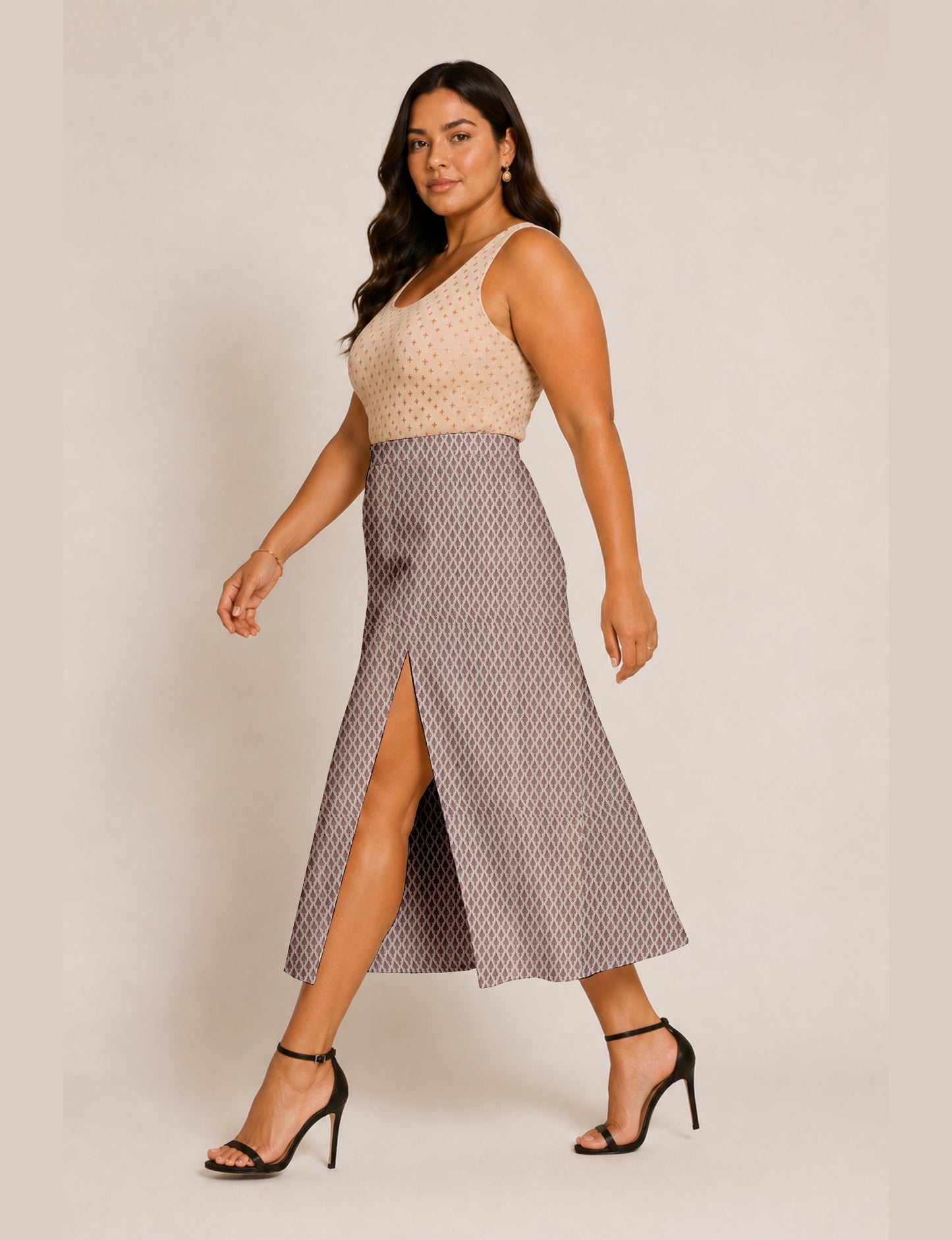Woman wearing a yellow and black micro patterned A-line skirt with front slit, paired with beige sleeveless top and black