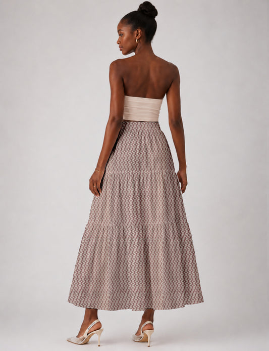 Woman wearing a yellow midi tiered skirt with a small geometric pattern, paired with a beige strapless top and white heels
