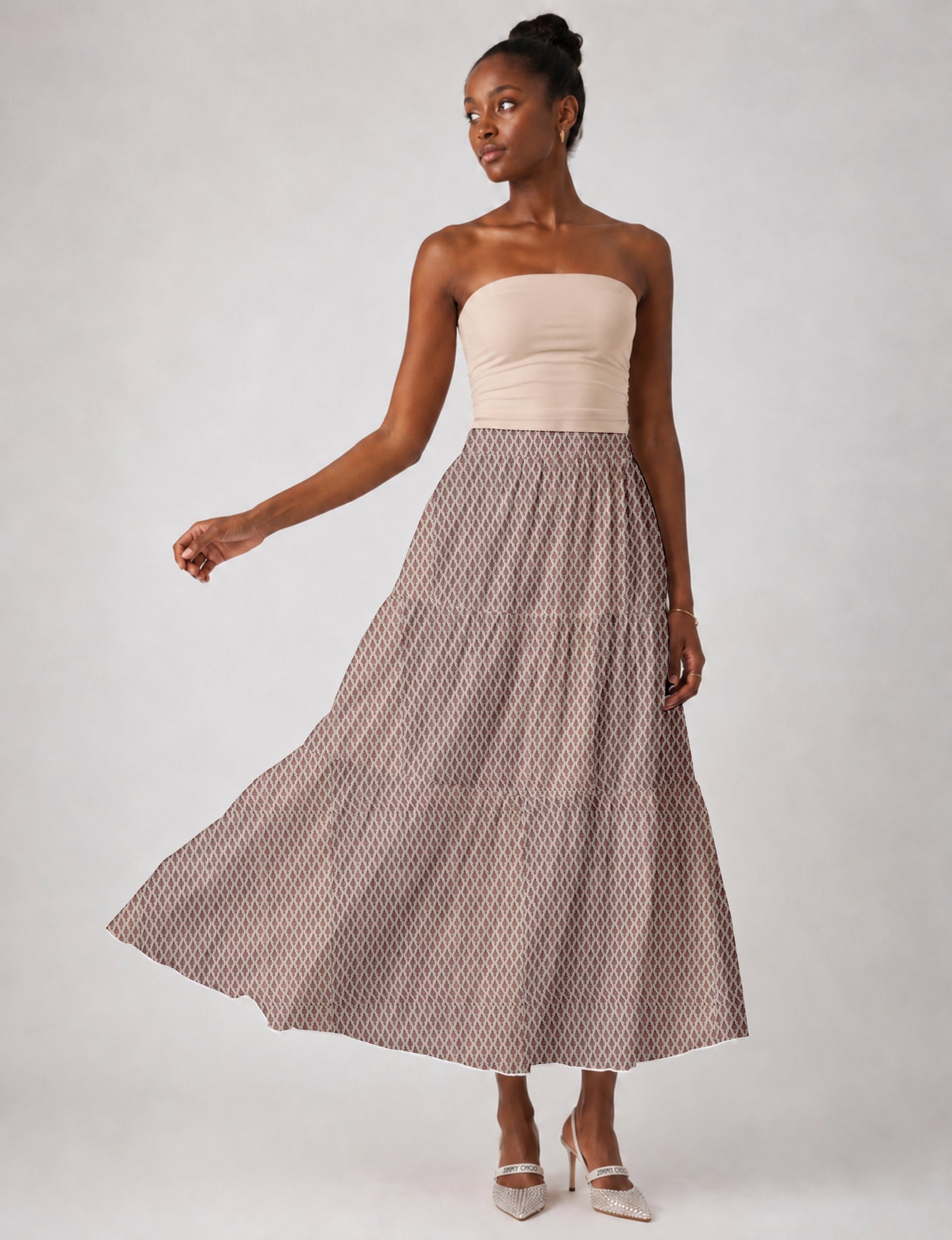 Woman wearing a yellow midi tiered skirt with a small geometric pattern, shown from the back, paired with beige top and