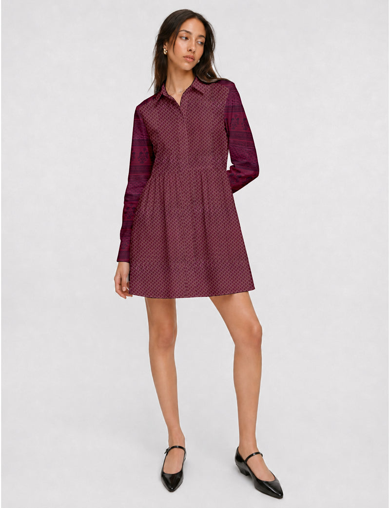 Model wearing a short pink shirt dress with a small leaf pattern, long sleeves, collar, and black Mary Jane shoes