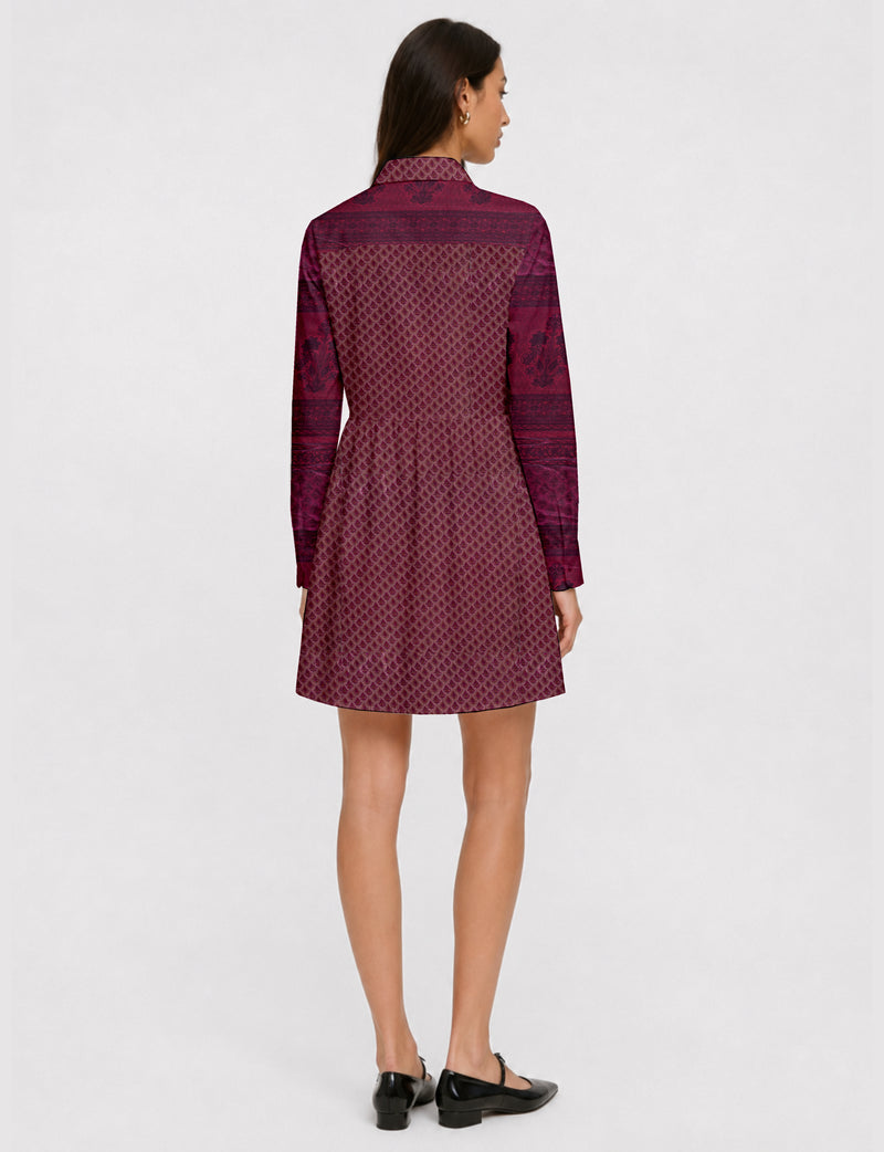 Woman wearing a short pink shirt dress with long sleeves and a small leaf pattern, shown from the back