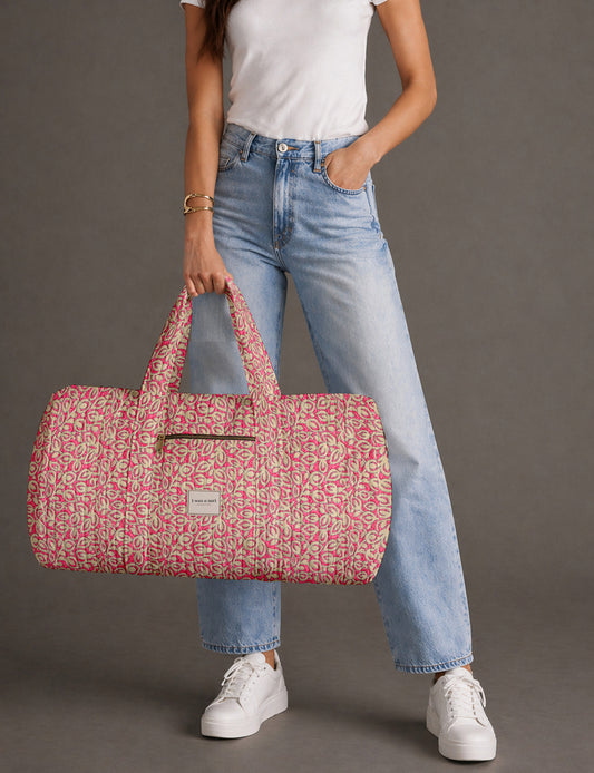 Quilted brown paisley barrel bag with double handles, front pocket, and gold zipper, shown in side angle view