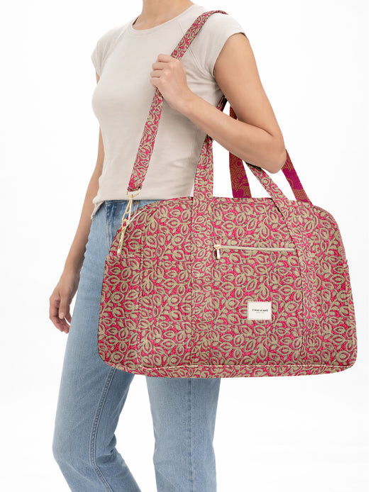 Brown quilted duffle bag with paisley pattern, front zip pocket, dual handles, and label reading "I was a sari"