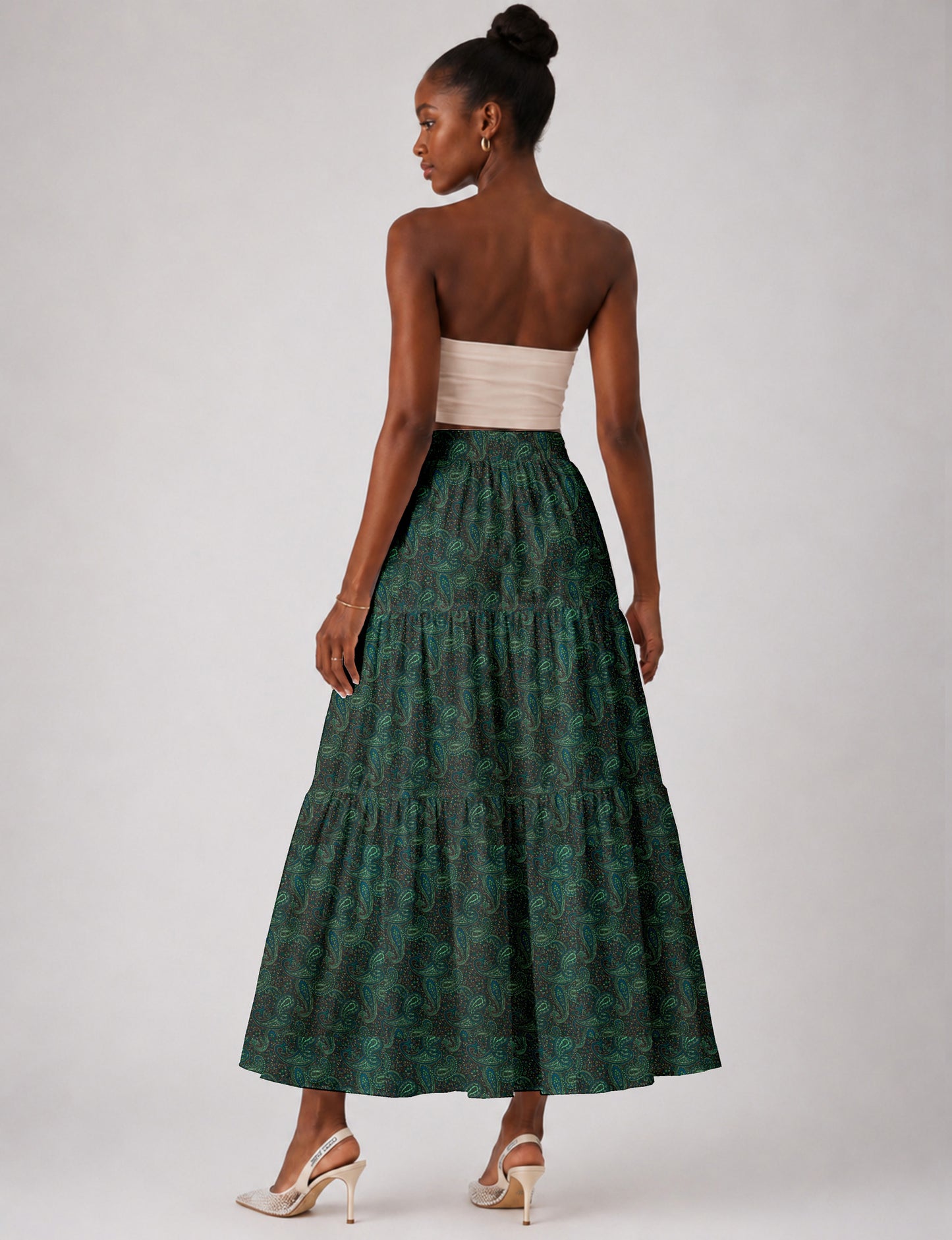 Woman wearing a yellow midi tiered skirt with a small geometric pattern, paired with a beige strapless top and white heels