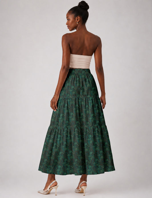 Woman wearing a yellow midi tiered skirt with a small geometric pattern, paired with a beige strapless top and white heels