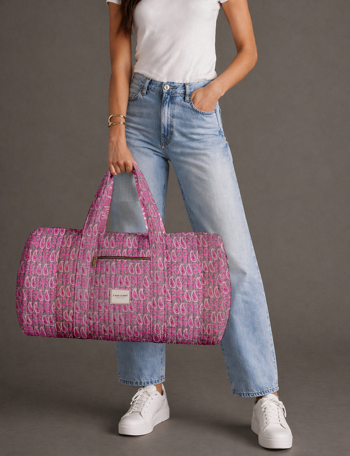 Quilted brown paisley barrel bag with double handles, front pocket, and gold zipper, shown in side angle view