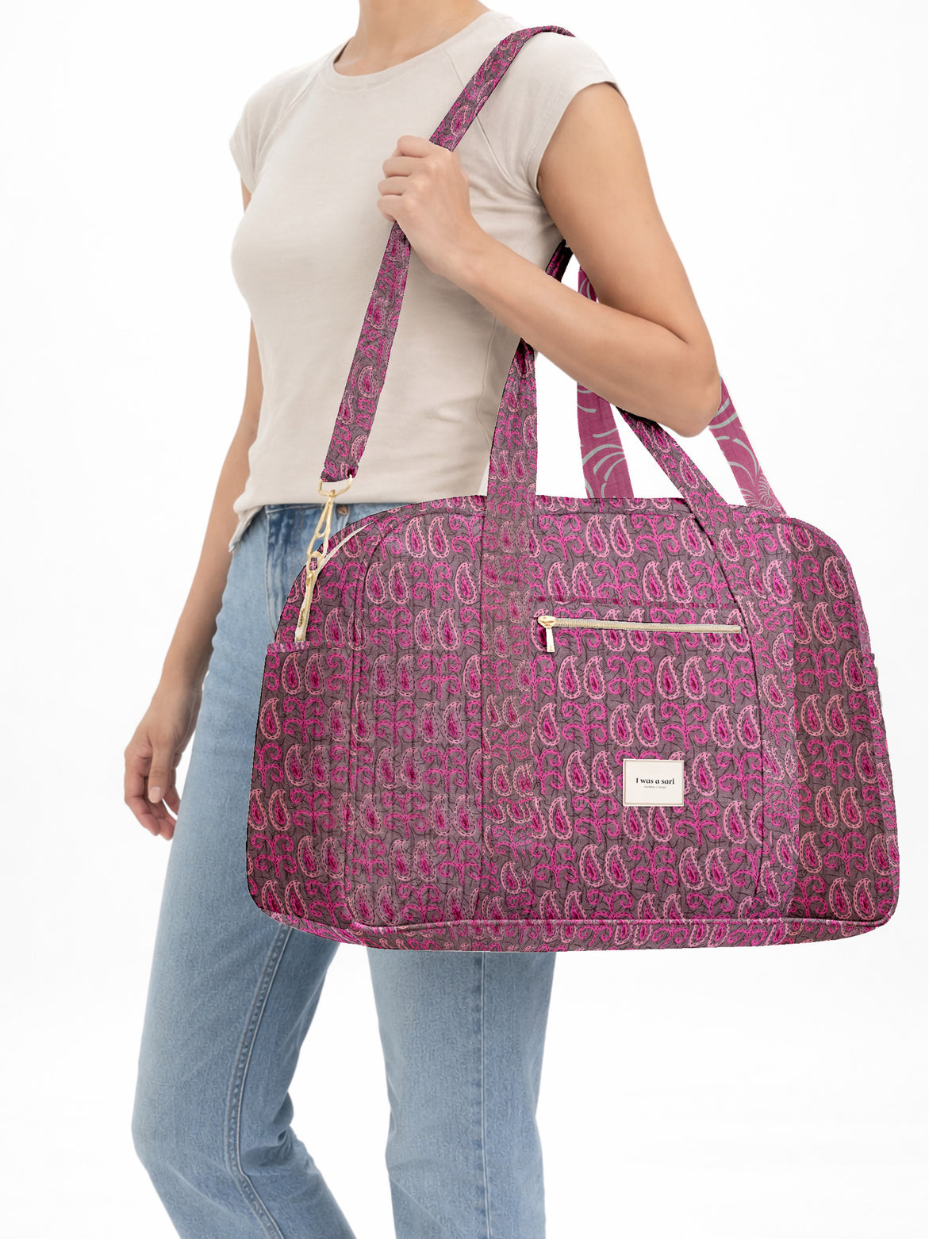 Brown quilted duffle bag with paisley pattern, front zip pocket, dual handles, and label reading "I was a sari"