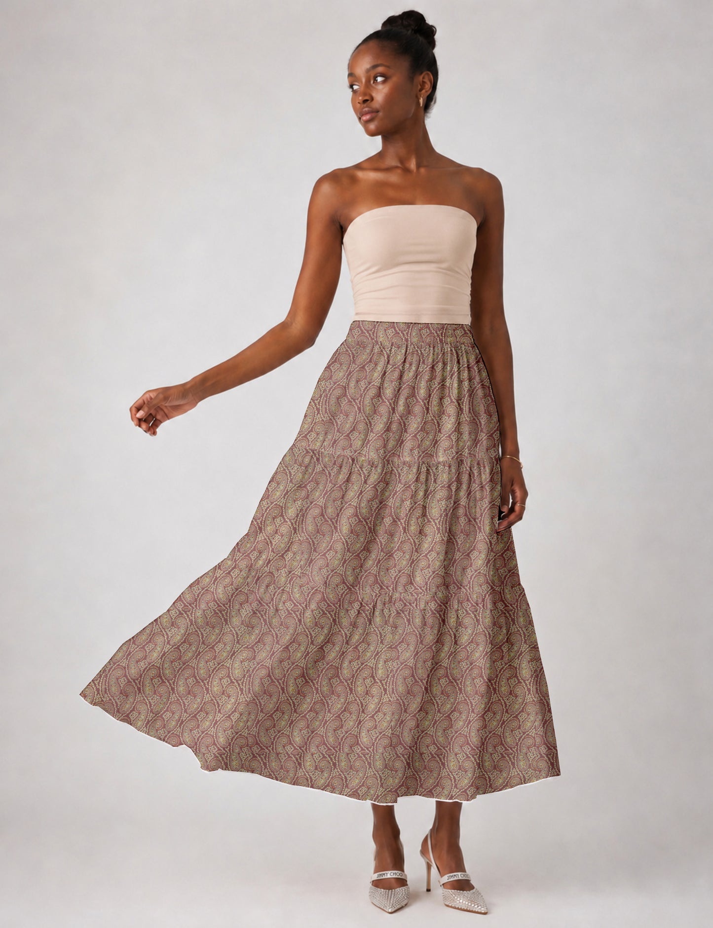 Woman wearing a yellow midi tiered skirt with a small geometric pattern, shown from the back, paired with beige top and