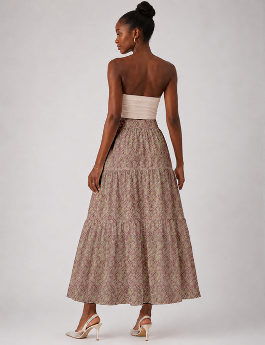 Woman wearing a yellow midi tiered skirt with a small geometric pattern, paired with a beige strapless top and white heels
