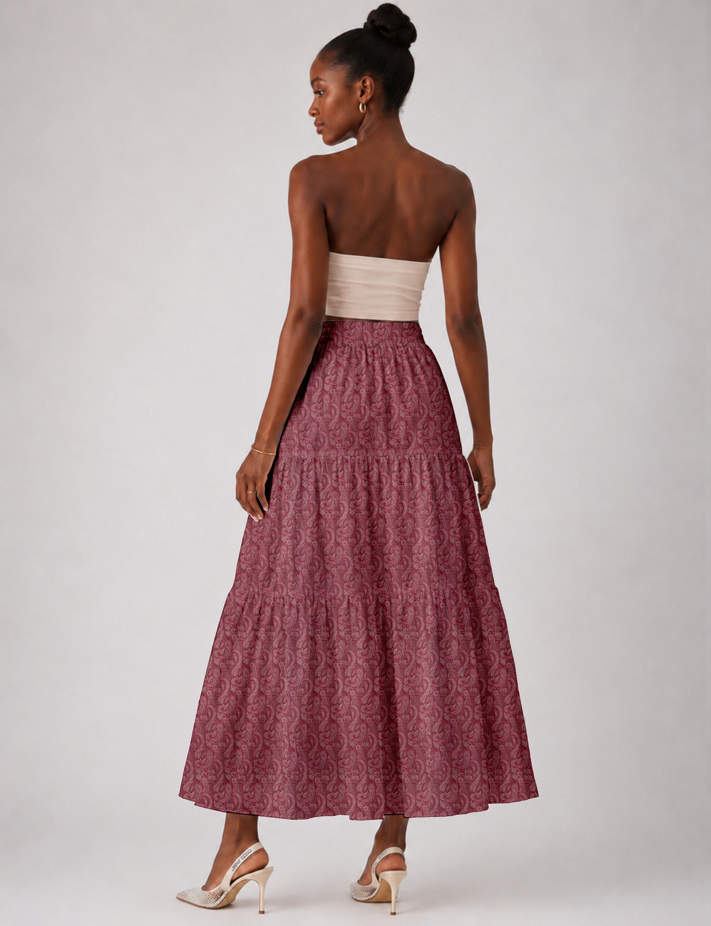 Woman wearing a yellow midi tiered skirt with a small geometric pattern, paired with a beige strapless top and white heels