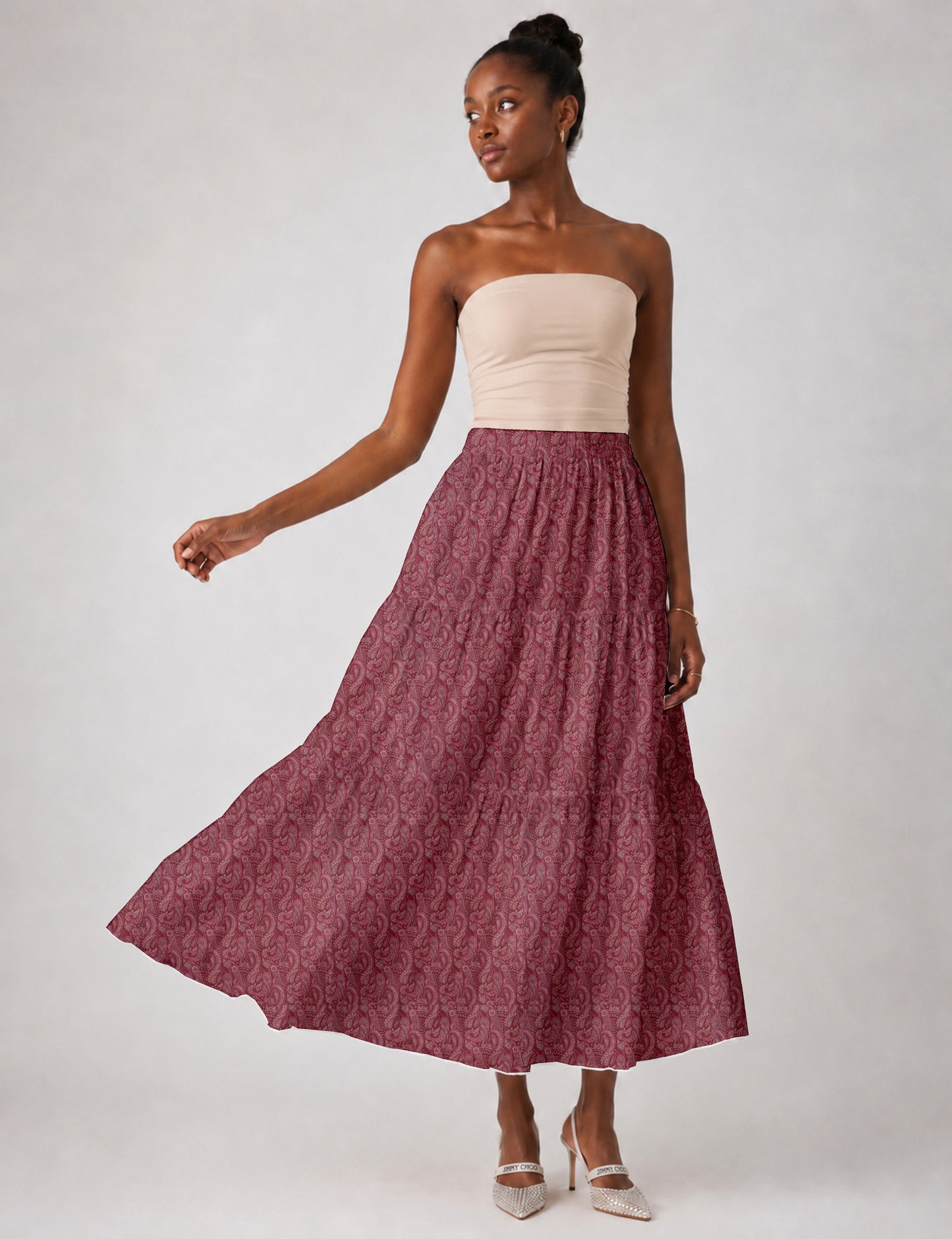 Woman wearing a yellow midi tiered skirt with a small geometric pattern, shown from the back, paired with beige top and