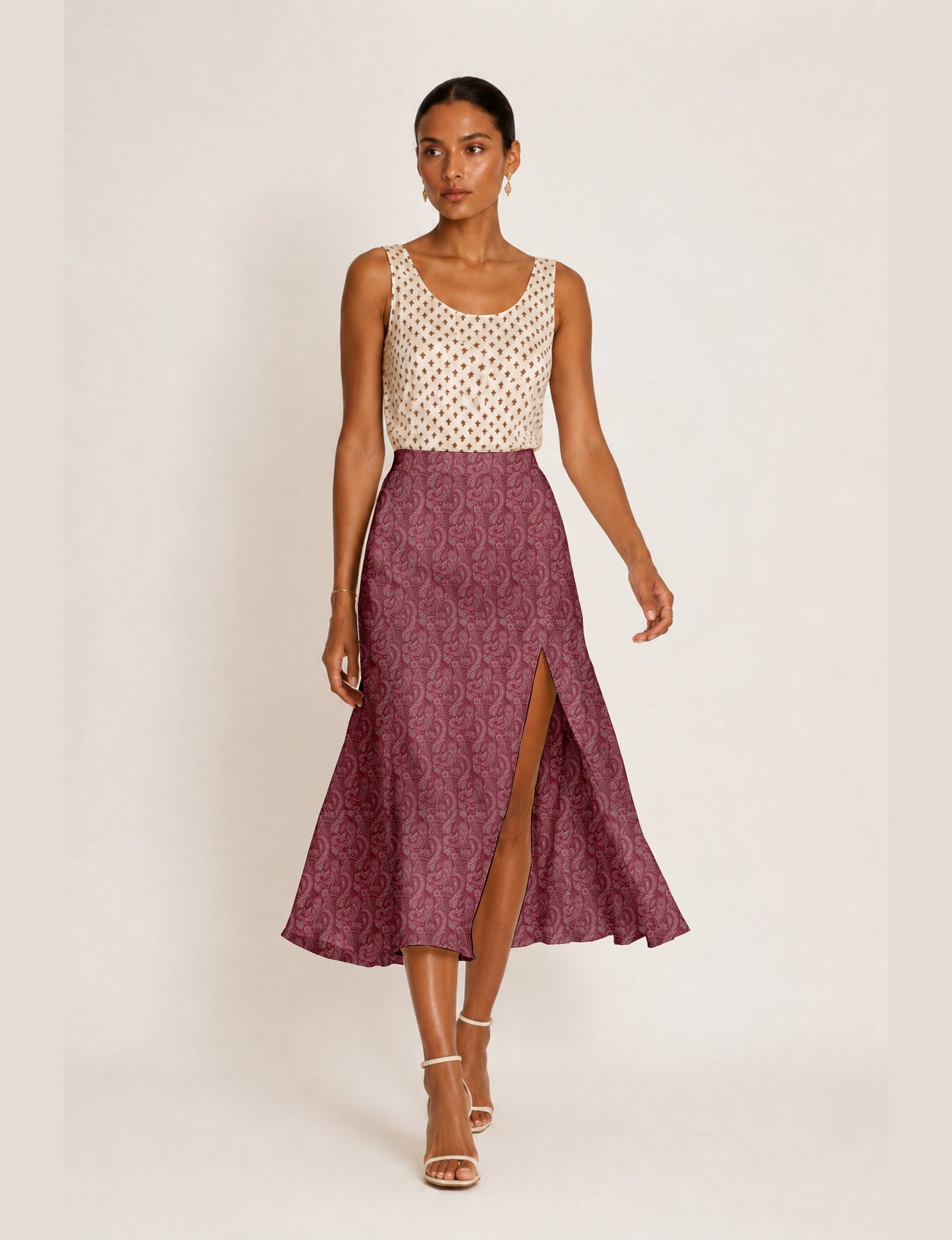 Woman wearing a yellow and black micro patterned A-line skirt with front slit, paired with beige sleeveless top and black