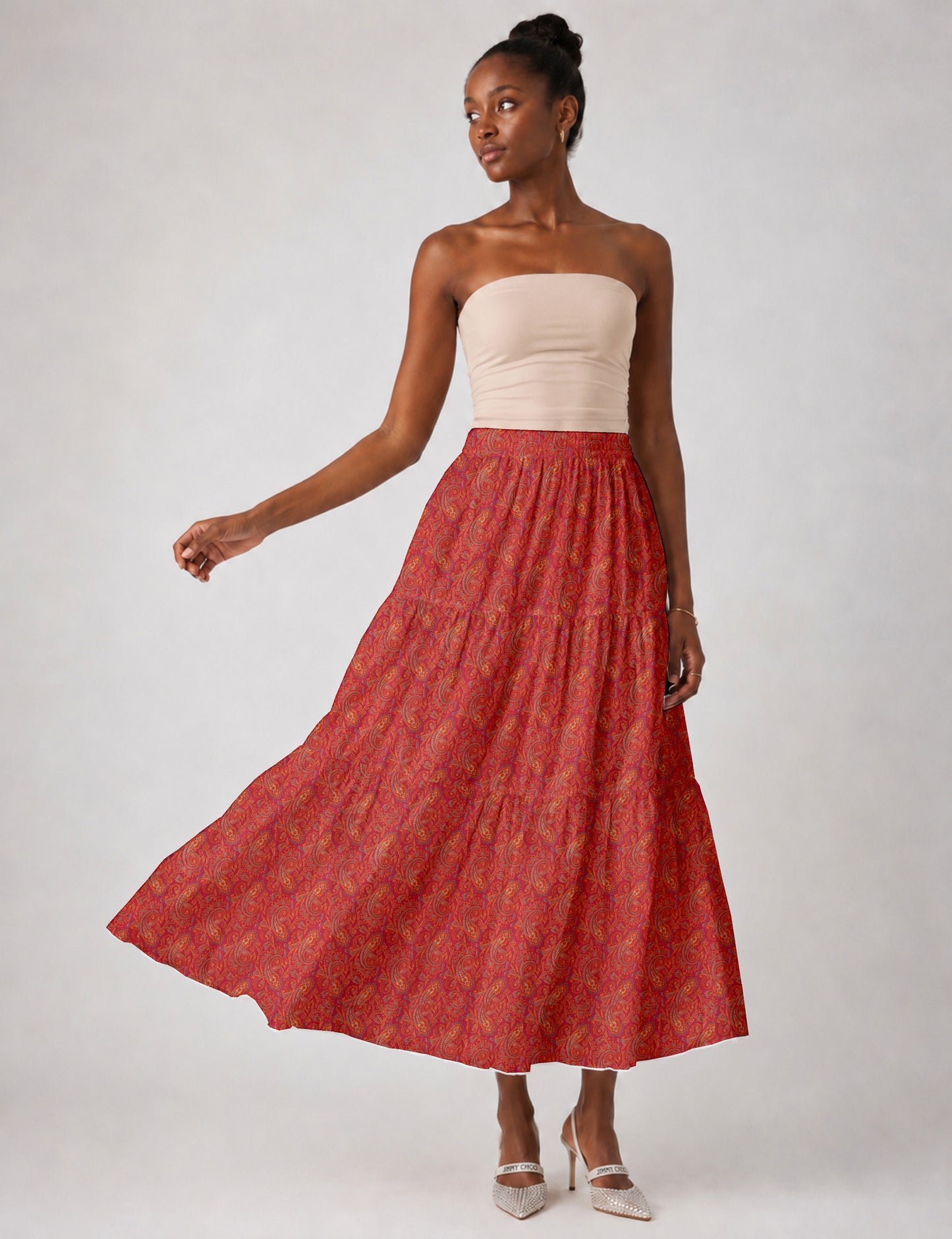 Woman wearing a yellow midi tiered skirt with a small geometric pattern, paired with a beige strapless top and white heels