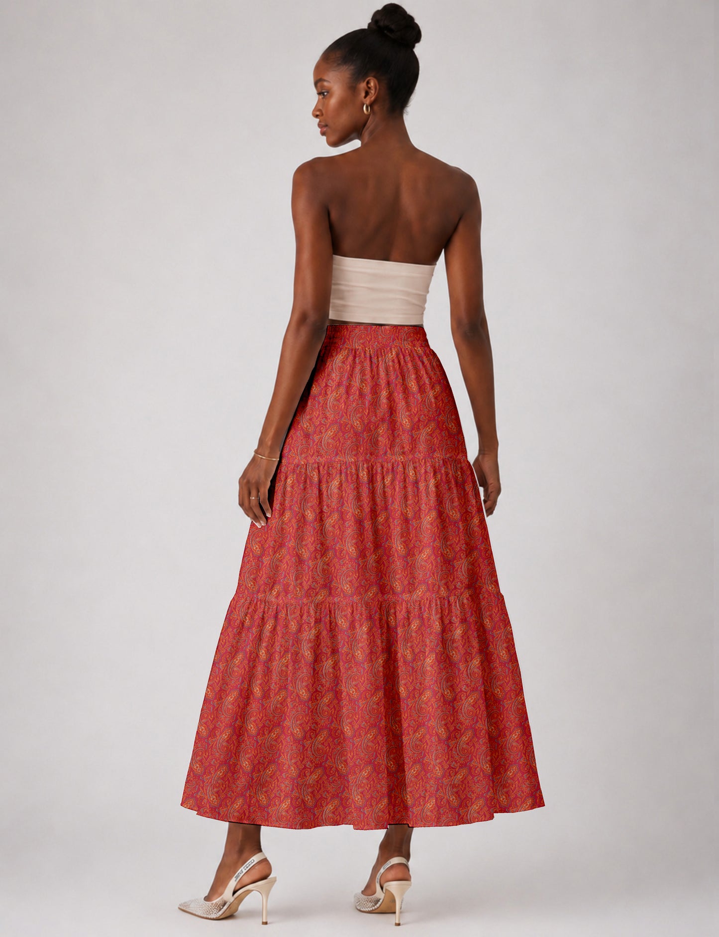 Woman wearing a yellow midi tiered skirt with a small geometric pattern, shown from the back, paired with beige top and