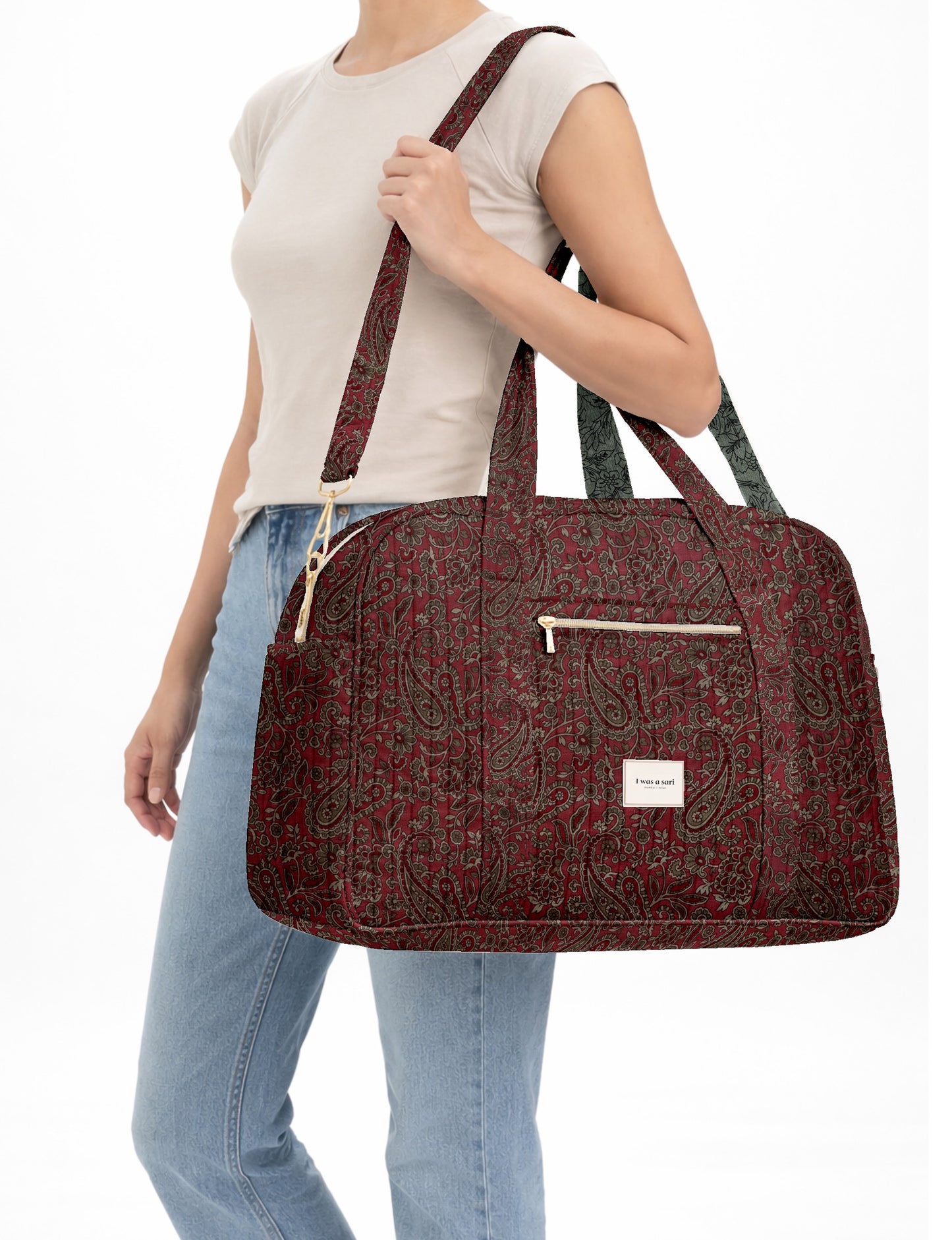 Brown quilted duffle bag with paisley pattern, front zip pocket, dual handles, and label reading "I was a sari"