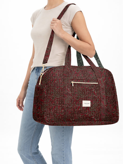 Brown quilted duffle bag with paisley pattern, front zip pocket, dual handles, and label reading "I was a sari"