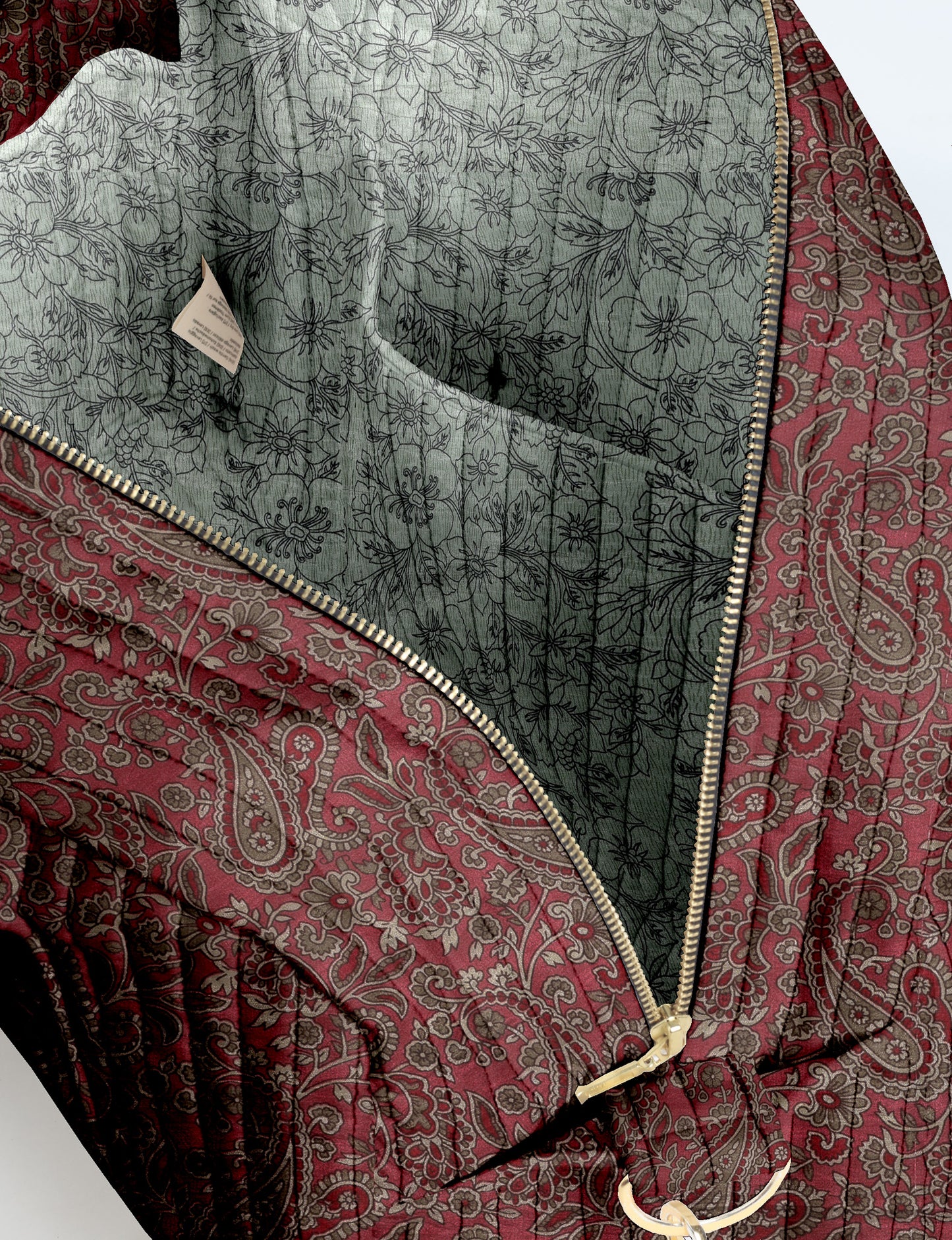 Brown quilted duffle bag with paisley pattern, front zip pocket, dual handles, and label reading "I was a sari"