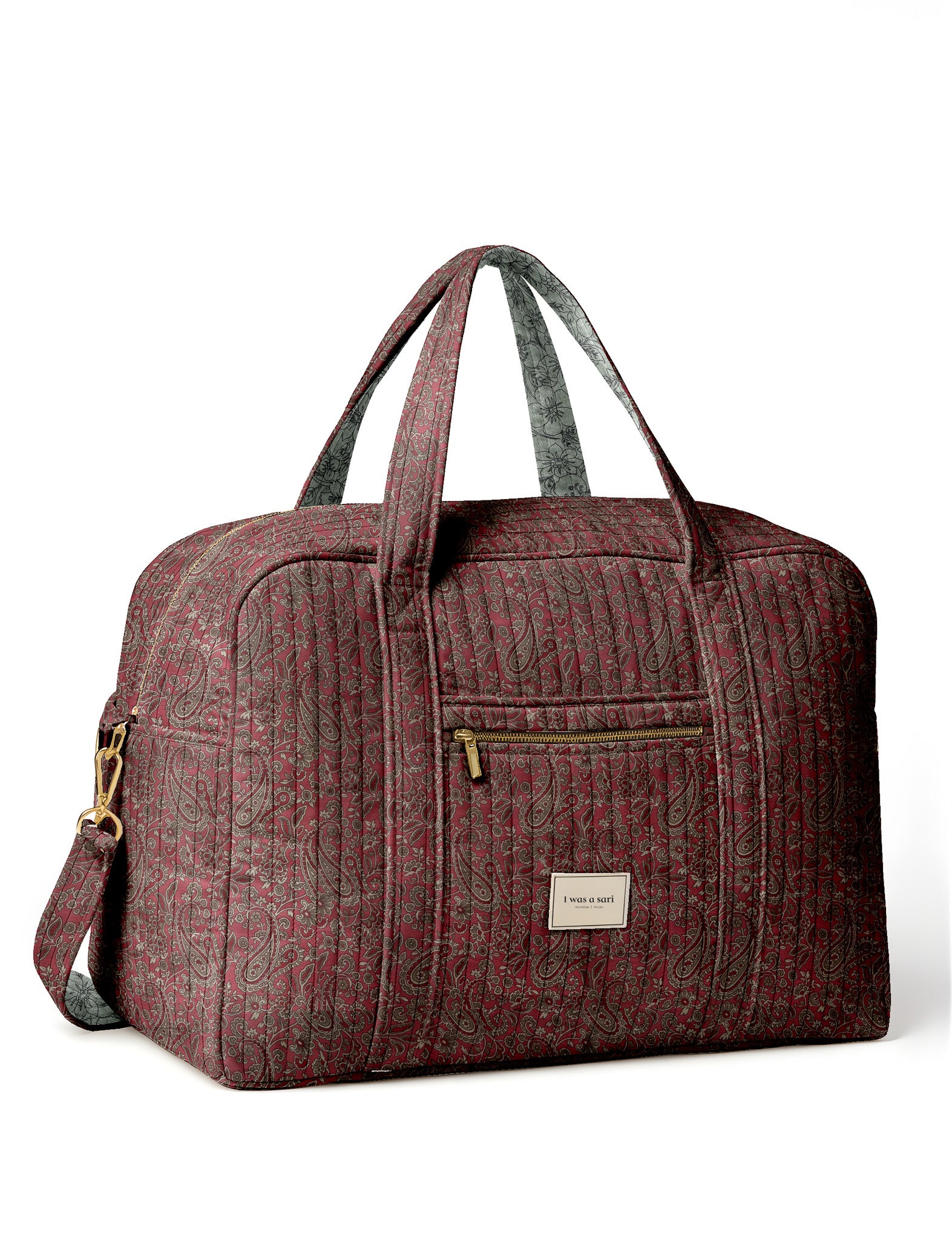 Brown quilted duffle bag with paisley pattern, front zip pocket, dual handles, and label reading "I was a sari"