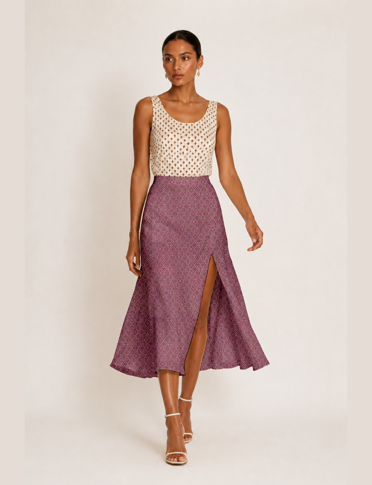 Woman wearing a yellow and black micro patterned A-line skirt with front slit, paired with beige sleeveless top and black