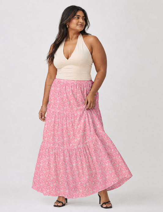 Woman wearing a yellow midi tiered skirt with a small geometric pattern, paired with a beige strapless top and white heels