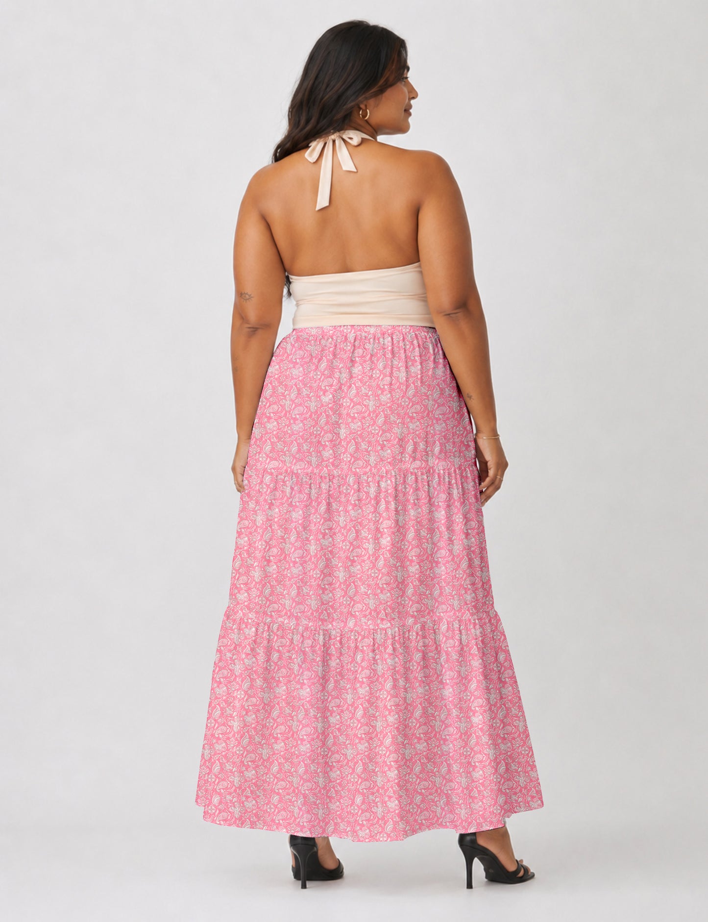 Woman wearing a yellow midi tiered skirt with a small geometric pattern, shown from the back, paired with beige top and