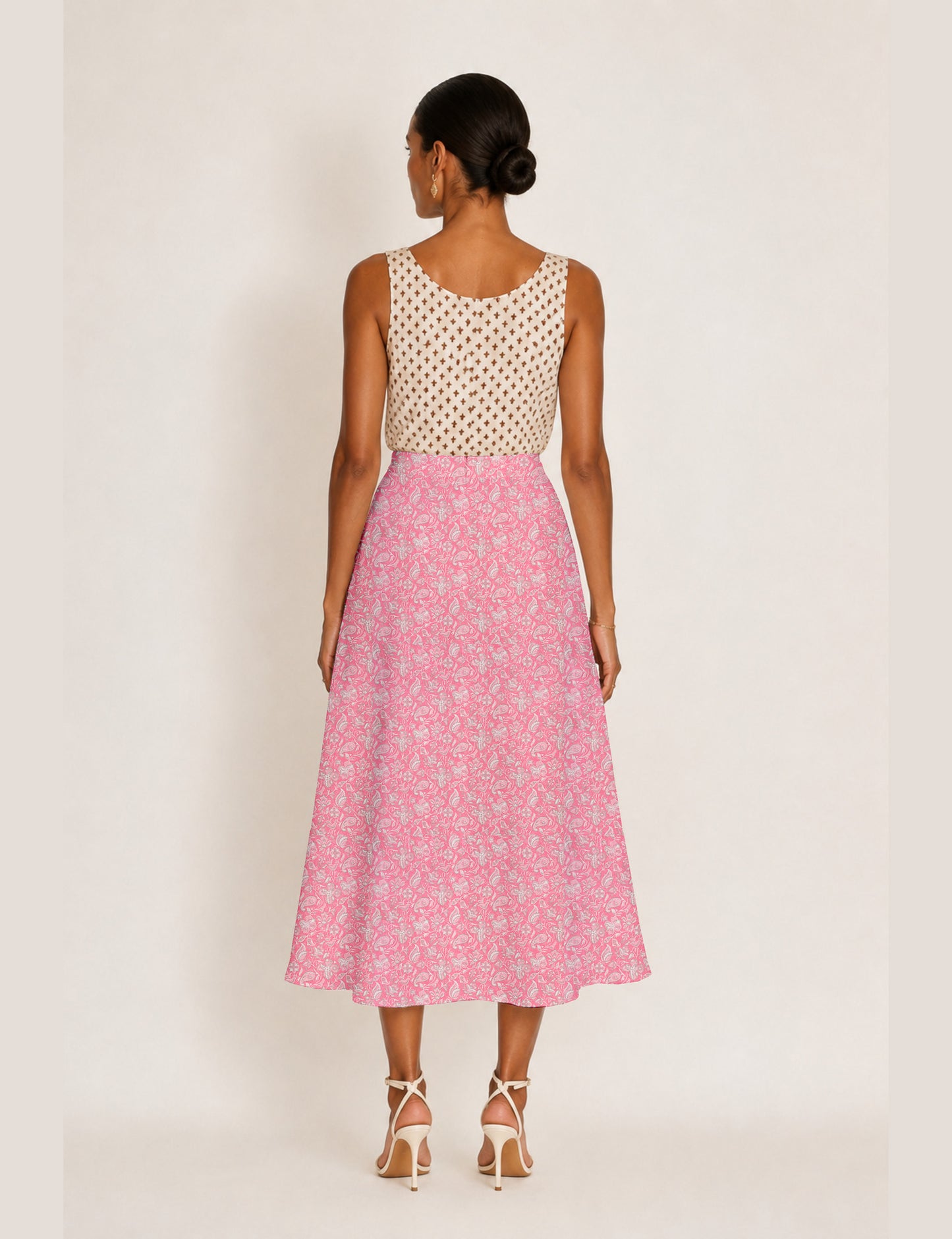 Woman wearing a yellow and black micro patterned A-line skirt with front slit, paired with beige sleeveless top and black
