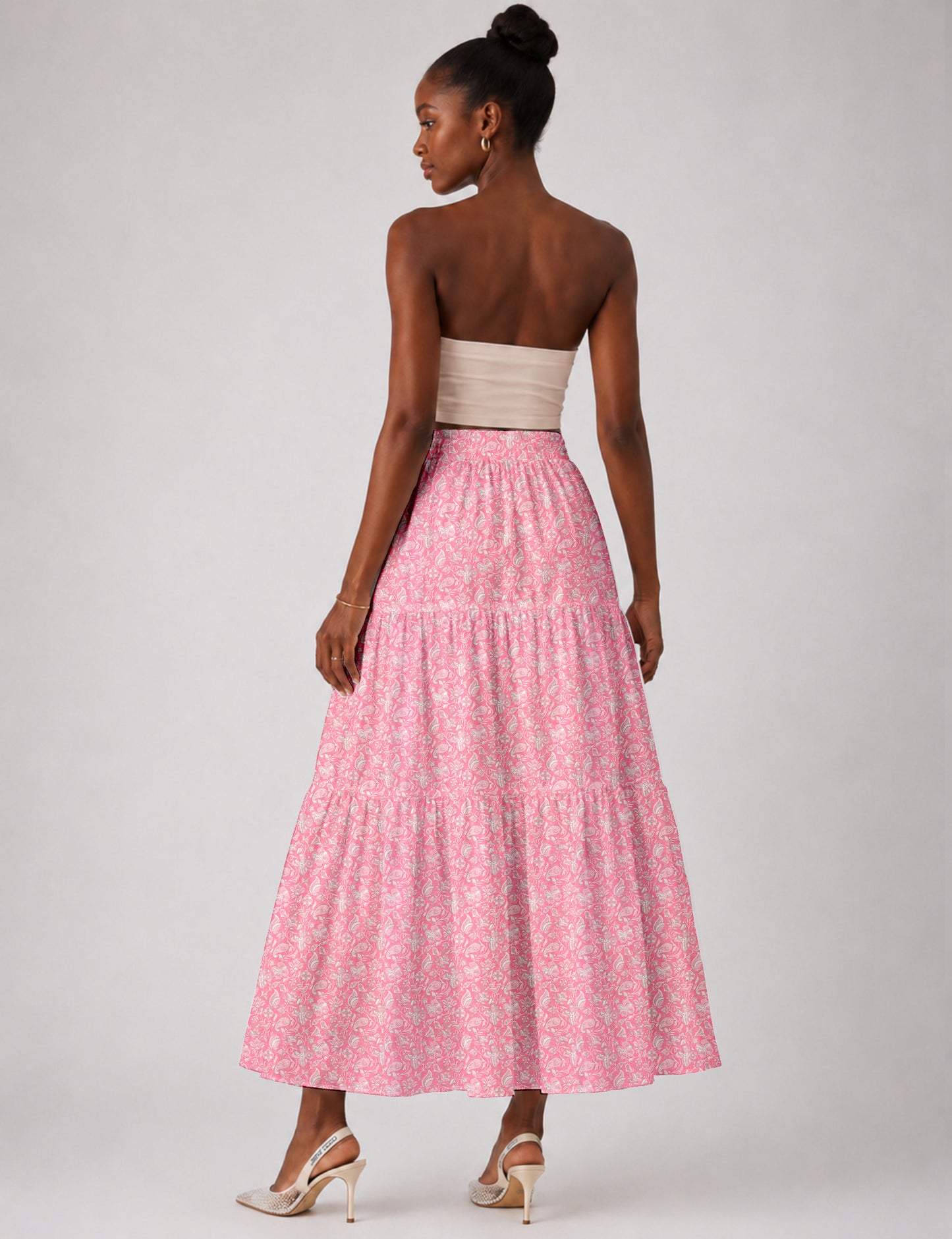 Woman wearing a yellow midi tiered skirt with a small geometric pattern, paired with a beige strapless top and white heels