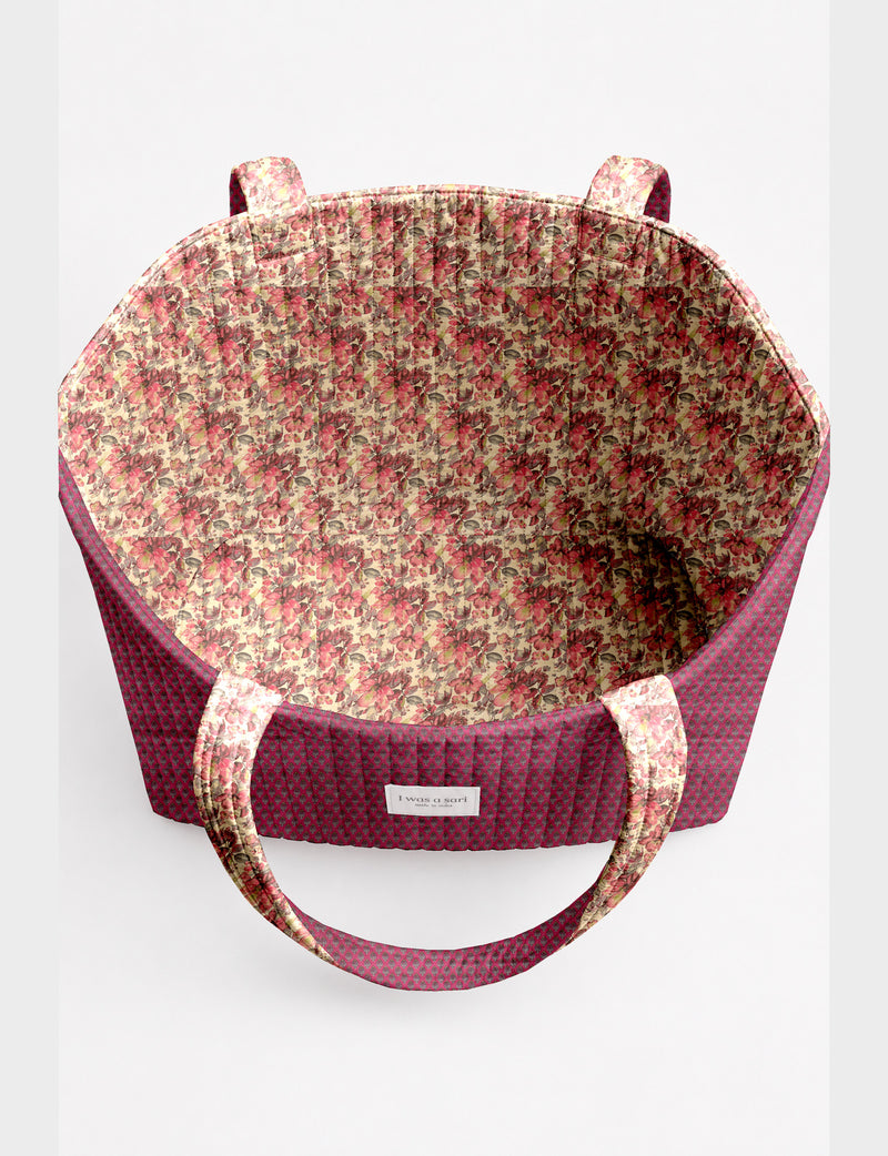 Quilted beach bag with yellow tropical exterior and red patterned interior, shown from top view with handles visible