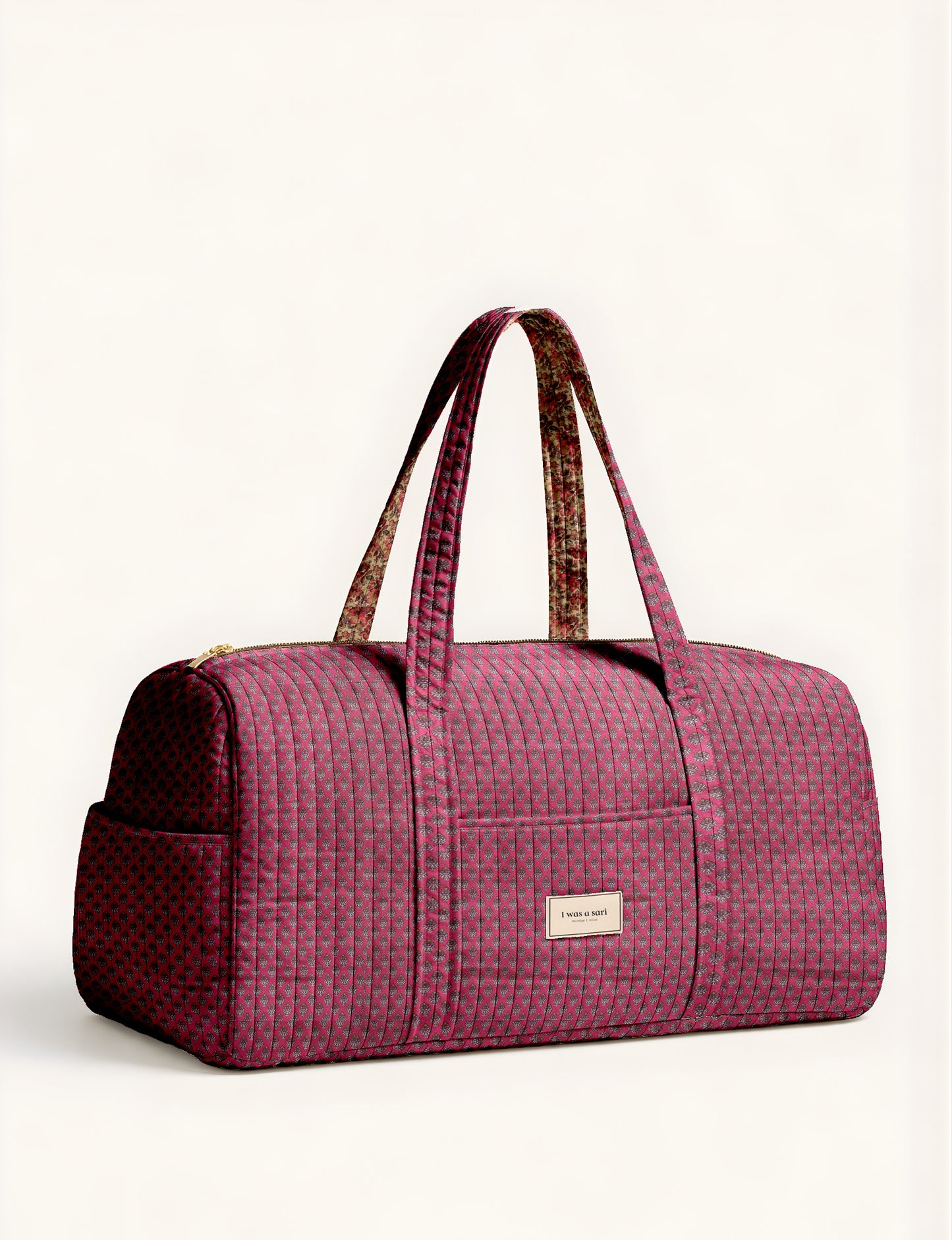 Quilted brown paisley barrel bag with double handles, front pocket, and gold zipper, shown in side angle view