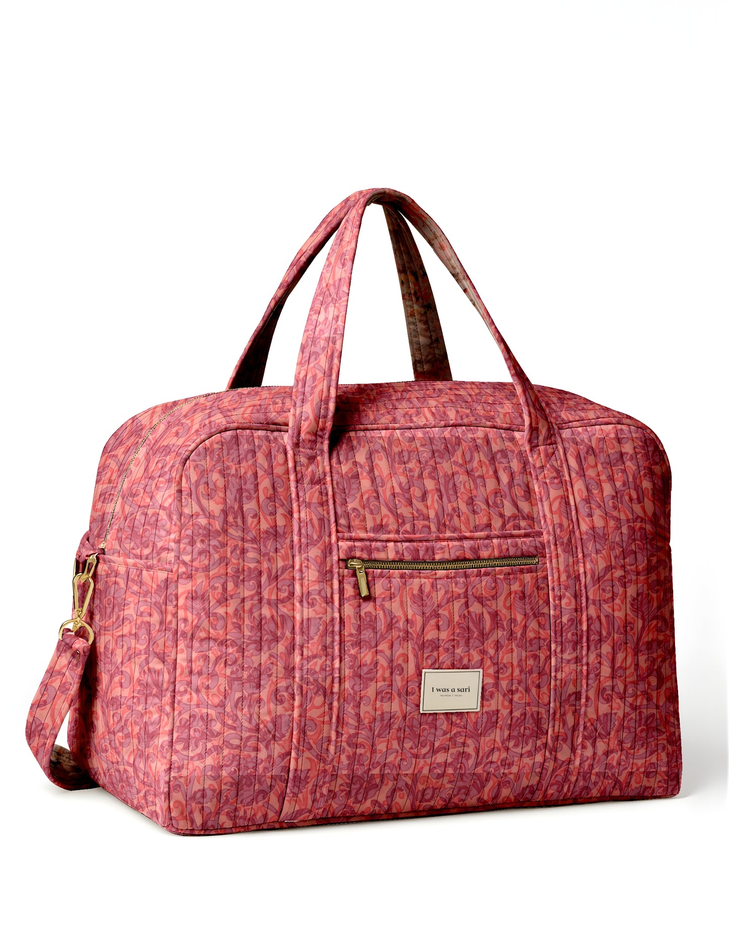 Quilted pink tropical patterned duffle bag with front zipper pocket, dual handles, and "I was a sari" label on front