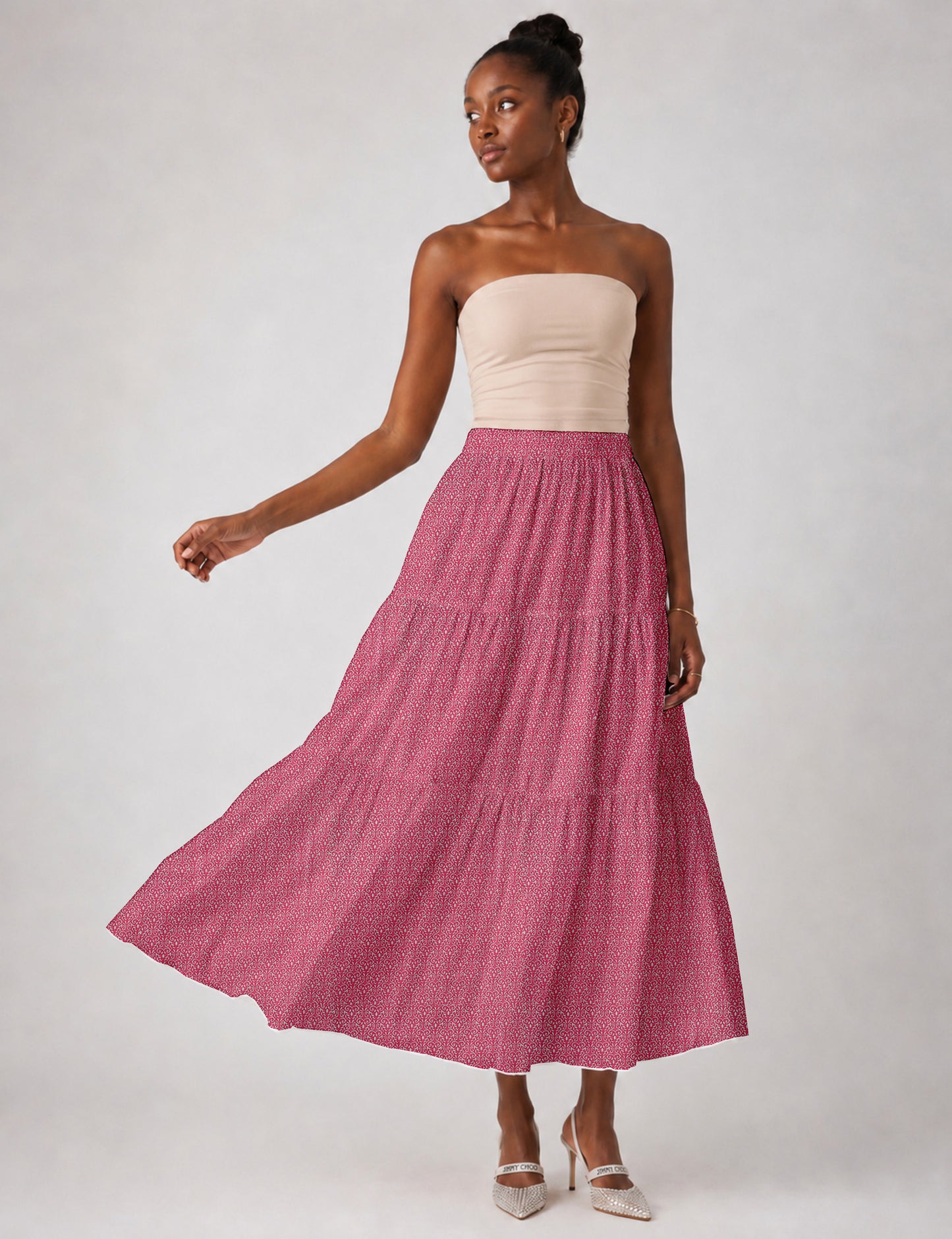 Woman wearing a yellow midi tiered skirt with a small geometric pattern, paired with a beige strapless top and white heels