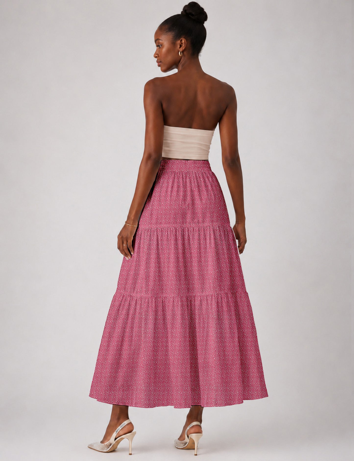 Woman wearing a yellow midi tiered skirt with a small geometric pattern, shown from the back, paired with beige top and