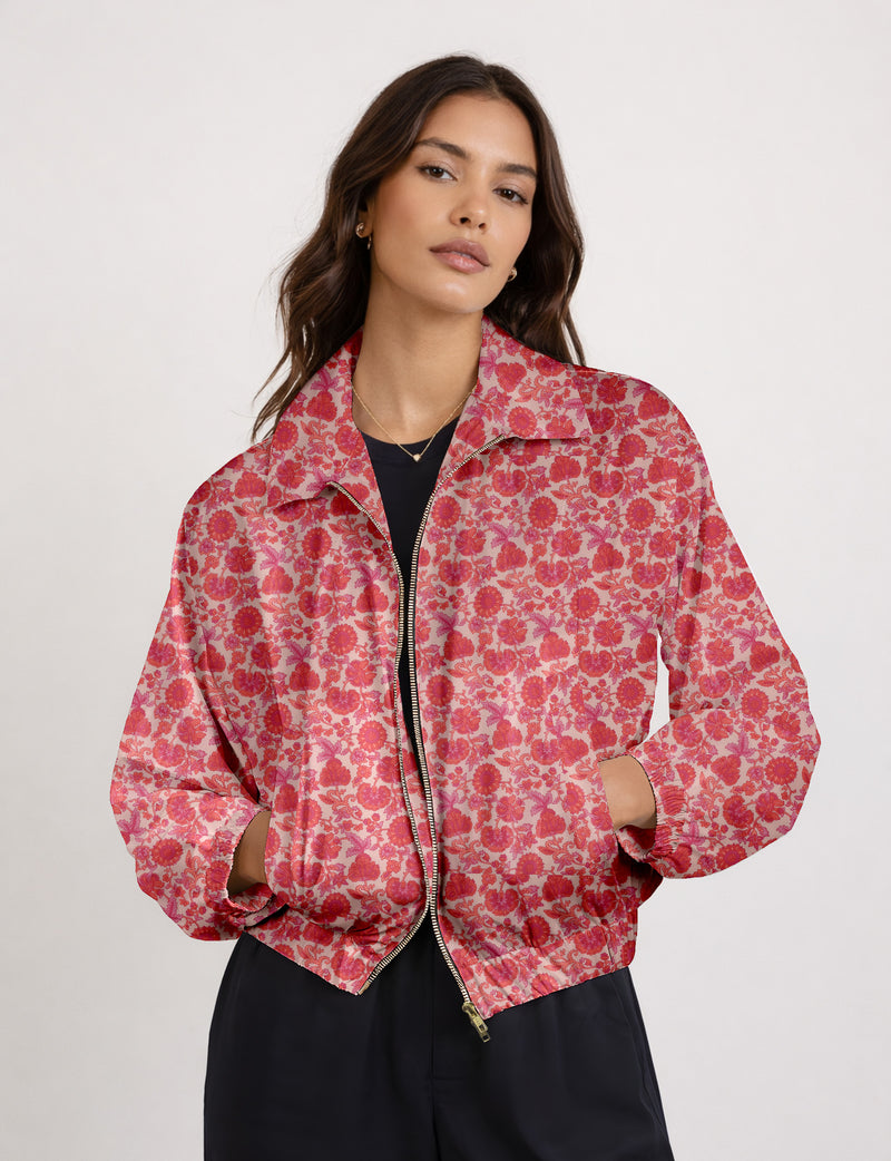Brown floral bomber jacket with front zipper, elastic cuffs and hem, hanging on white hanger, red floral inner lining visible