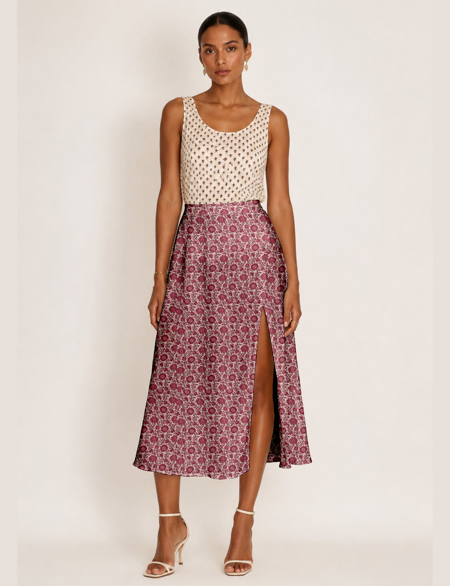 Woman wearing a yellow and black micro patterned A-line skirt with front slit, paired with beige sleeveless top and black