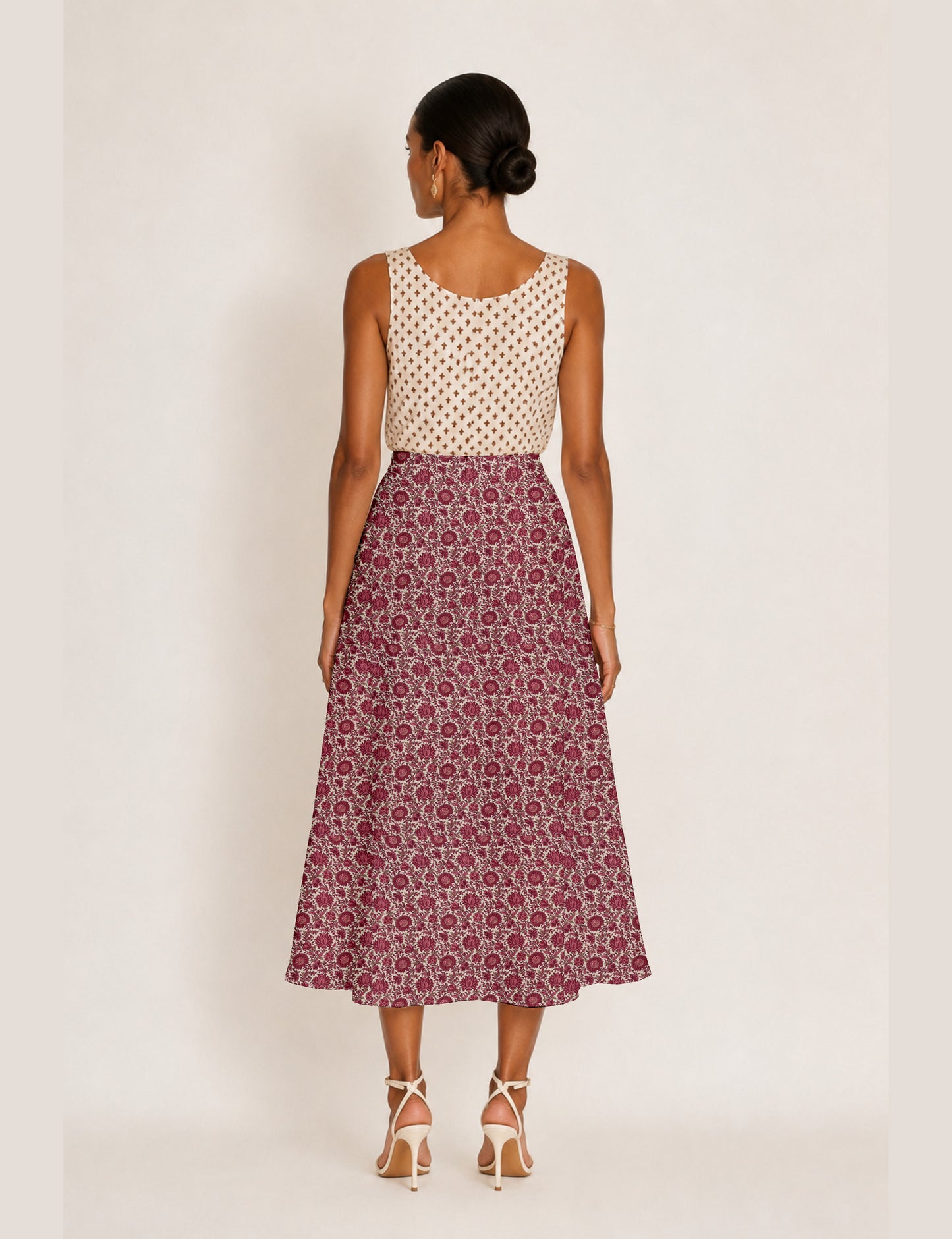 Woman wearing a yellow and black micro patterned A-line skirt with front slit, paired with beige sleeveless top and black
