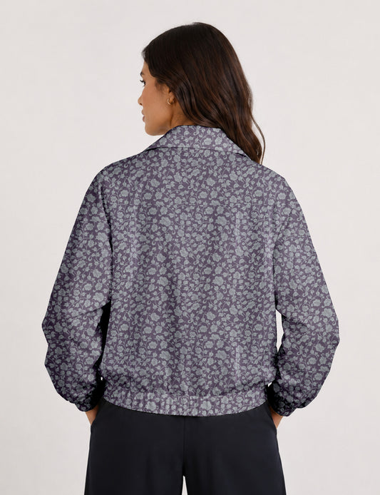 Woman wearing a yellow floral bomber jacket with front zipper, elastic cuffs, and side pockets, shown from front view