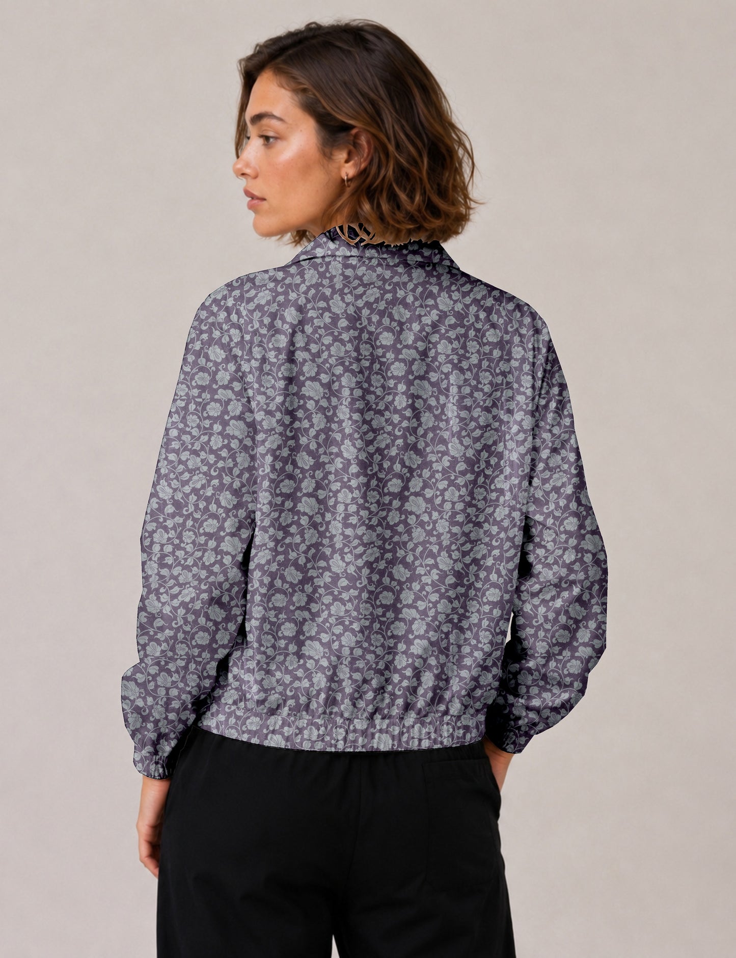 Woman wearing a yellow floral bomber jacket with front zipper, elastic cuffs, and side pockets, shown from front view